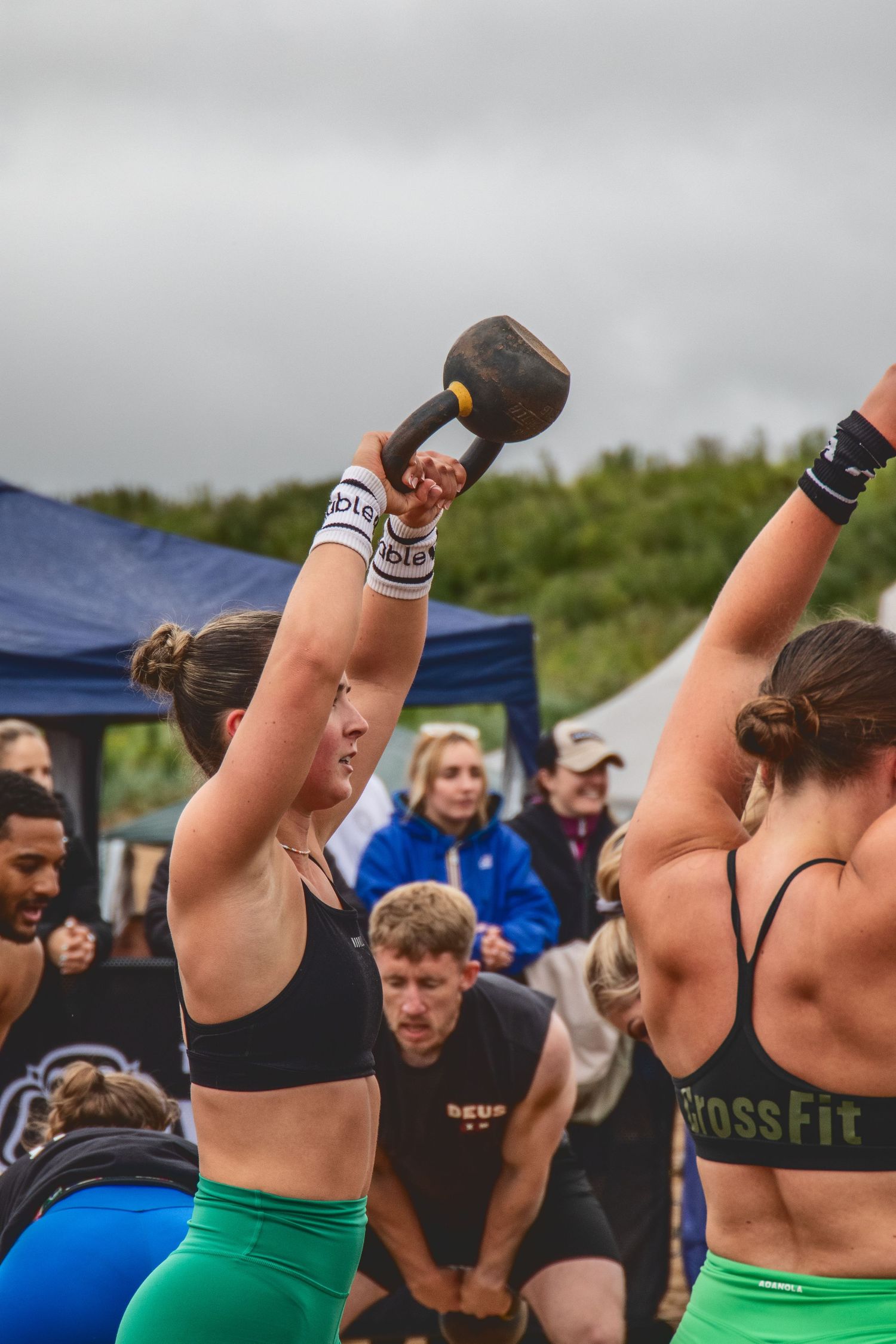 Athletes perform synchronized kettlebell swings during an outdoor CrossFit competition event.