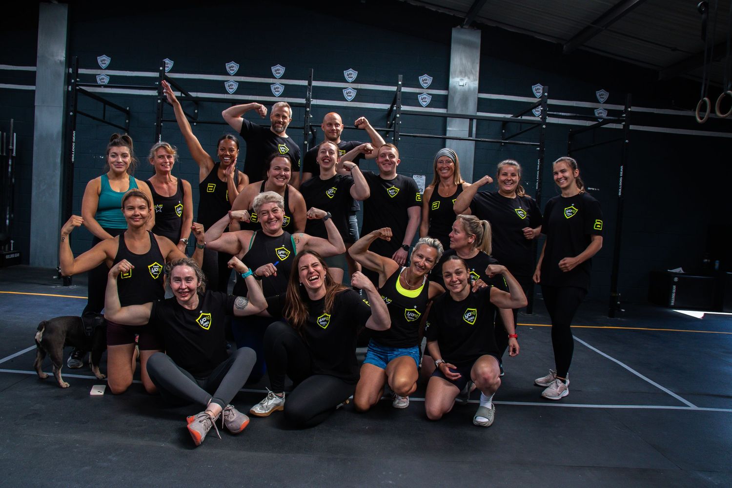 Group of fitness enthusiasts resting and posing together after a CrossFit workout in a gym.