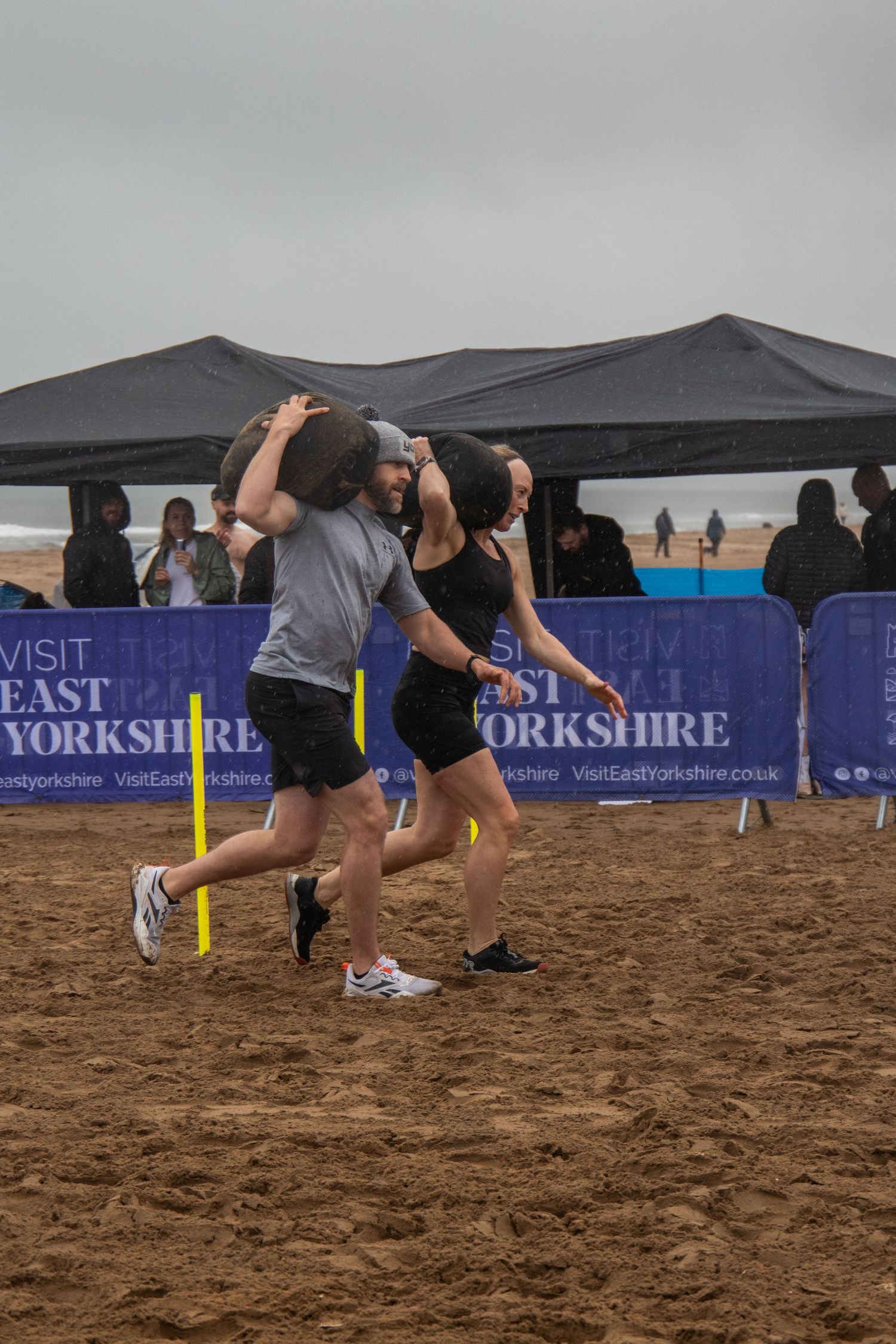 Competitors engage in a beach volleyball match at an East Yorkshire sporting event on sandy terrain.
