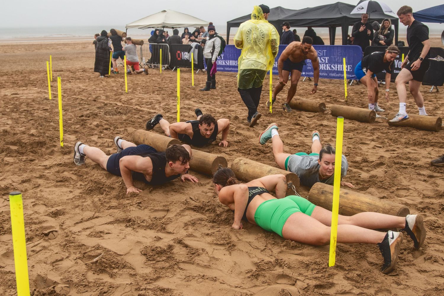 Beach fitness class participants do planks and core exercises in the sand during an outdoor workout session.