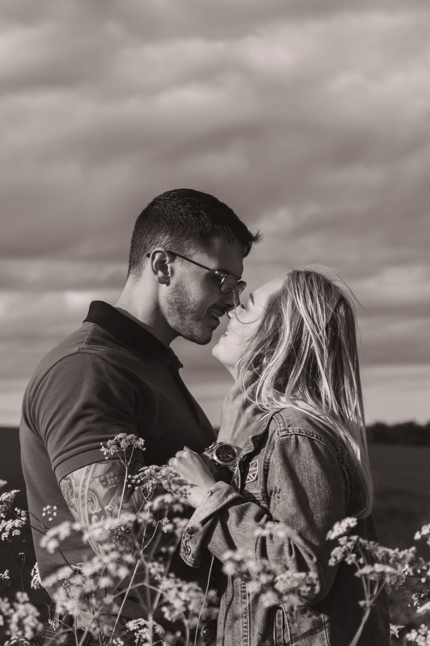 Black and white romantic portrait of couple surrounded by delicate flowers.