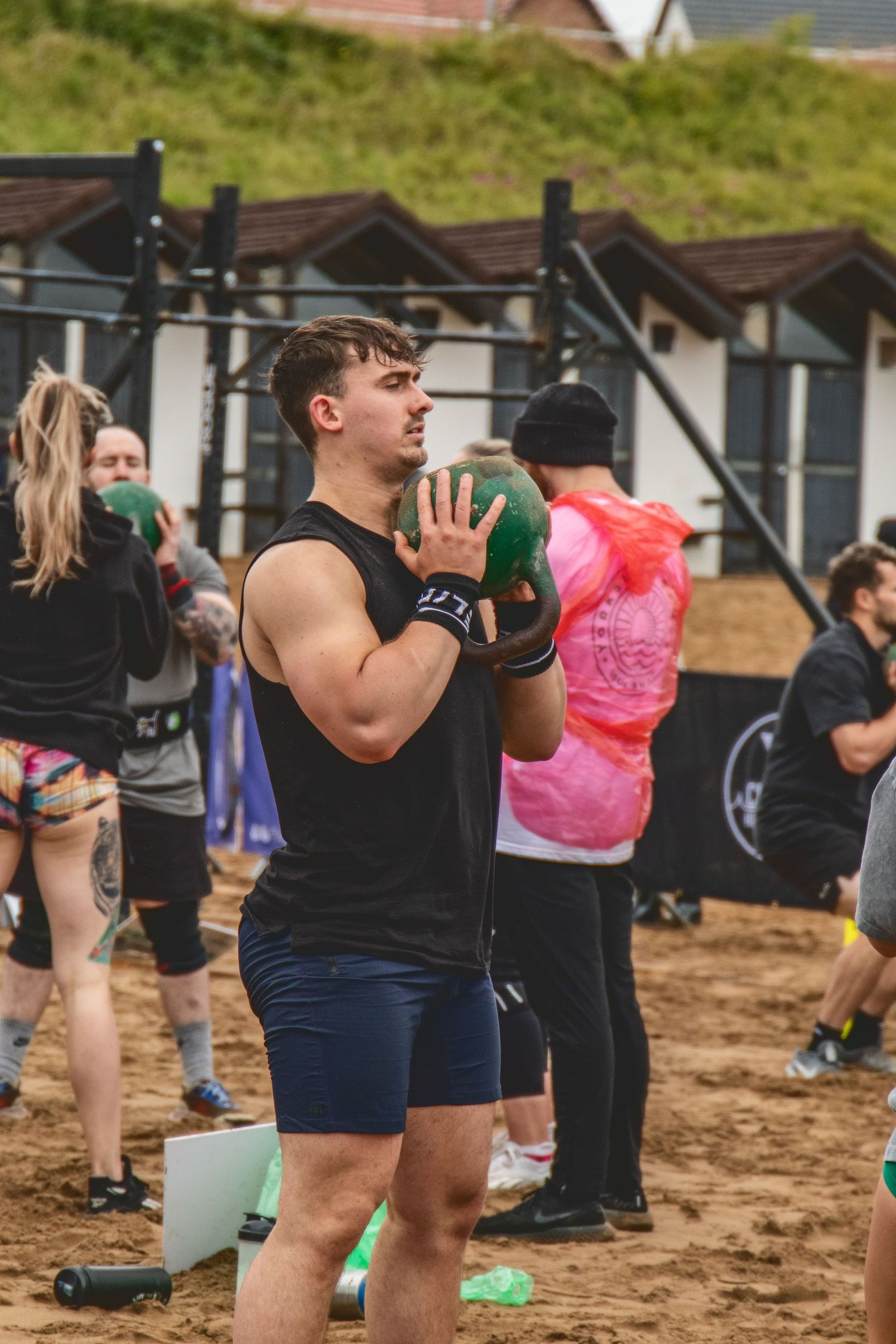 A group of athletes performs outdoor fitness exercises on sandy terrain during a group workout session.