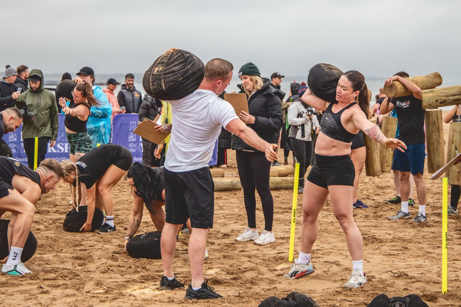 A group of people gather on a beach participating in a team building activity or competition.