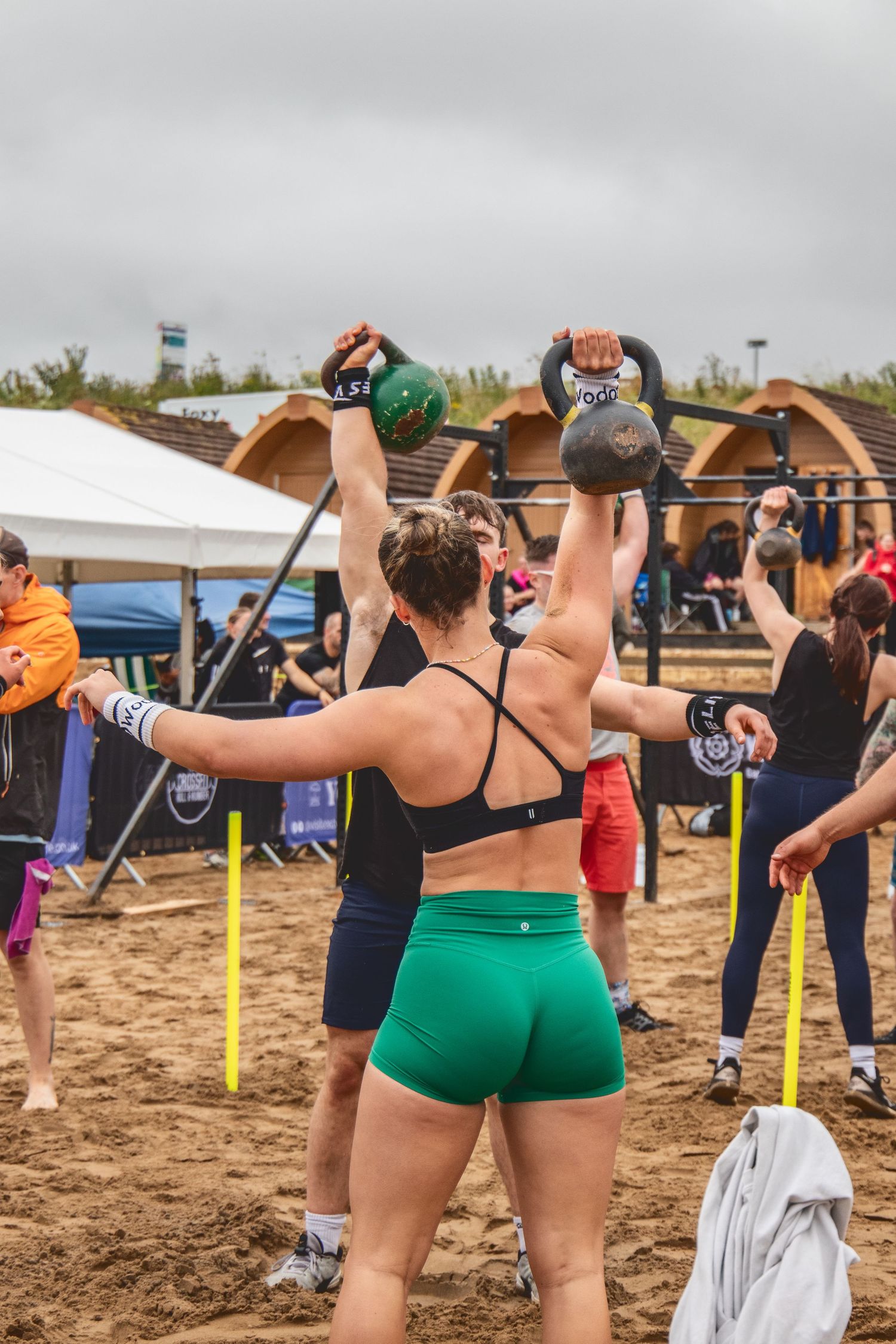 Groups of participants exercise outdoors on a beach with resistance bands during a fitness class session.