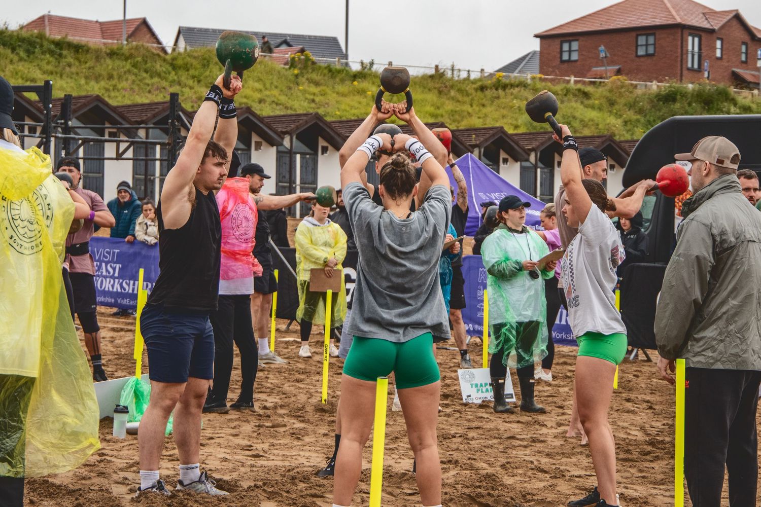 Athletic group participating in team-building exercises on a sandy beach during an outdoor fitness event.