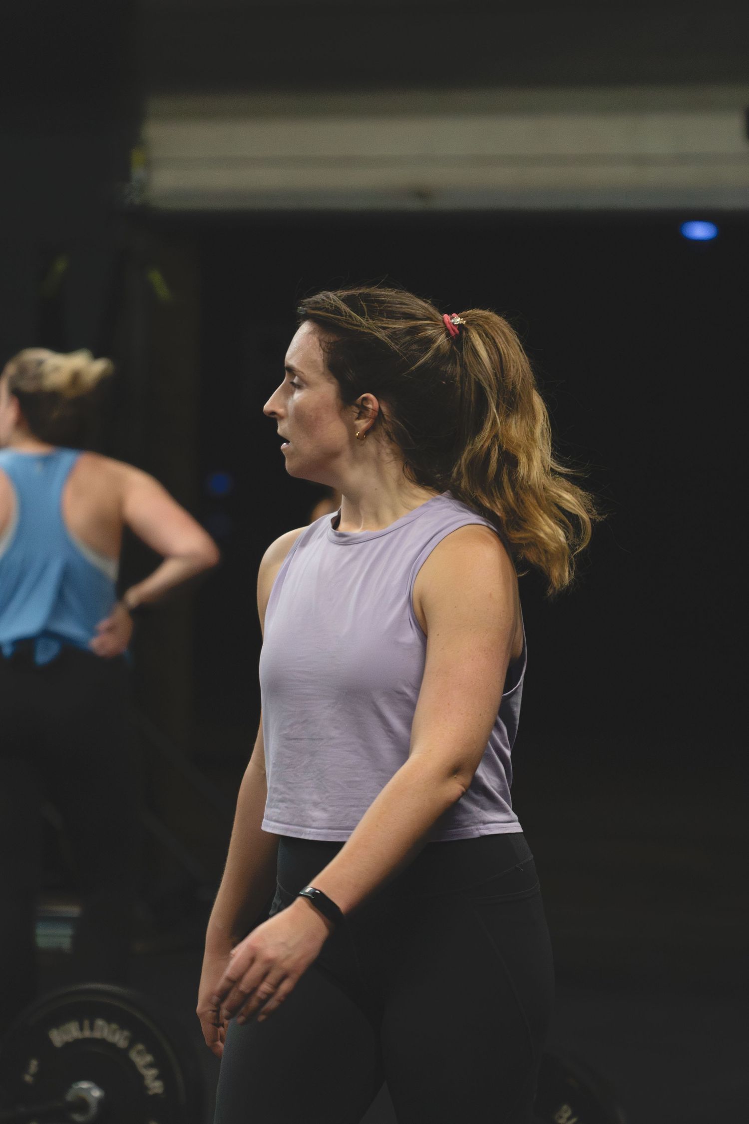 Athlete in a light purple tank top and black leggings training at a fitness facility.