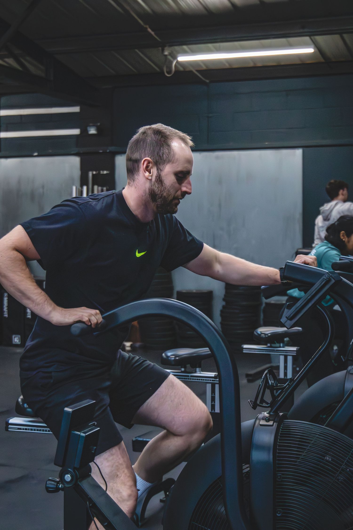 A sequence of gym workout photos showing someone exercising on a stationary bike in dark athletic clothing.