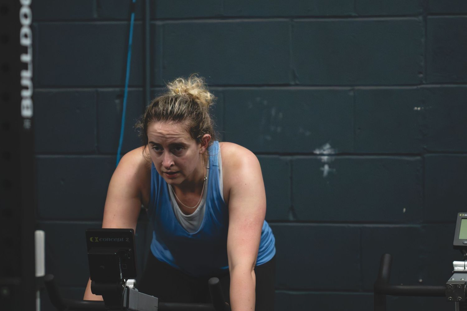 Athletes battle through an intense rowing machine workout in a dimly lit gym setting.