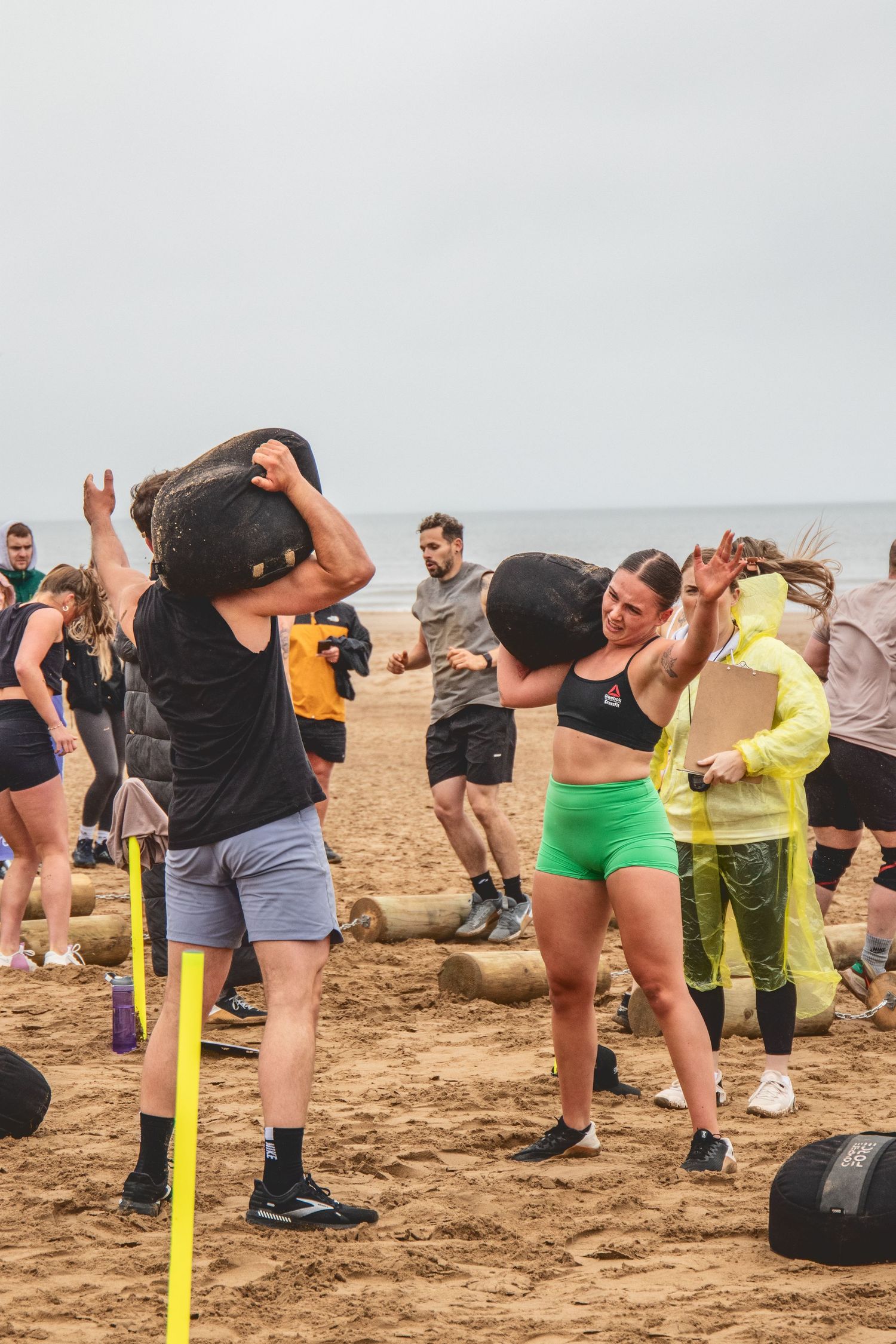 Group of athletes working out on a sandy beach with exercise equipment and fitness gear during outdoor training session.