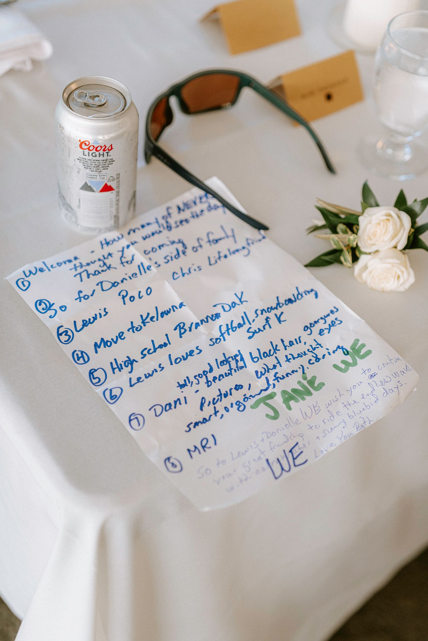 Handwritten guest messages and notes on white tablecloths at a wedding reception with floral decorations.