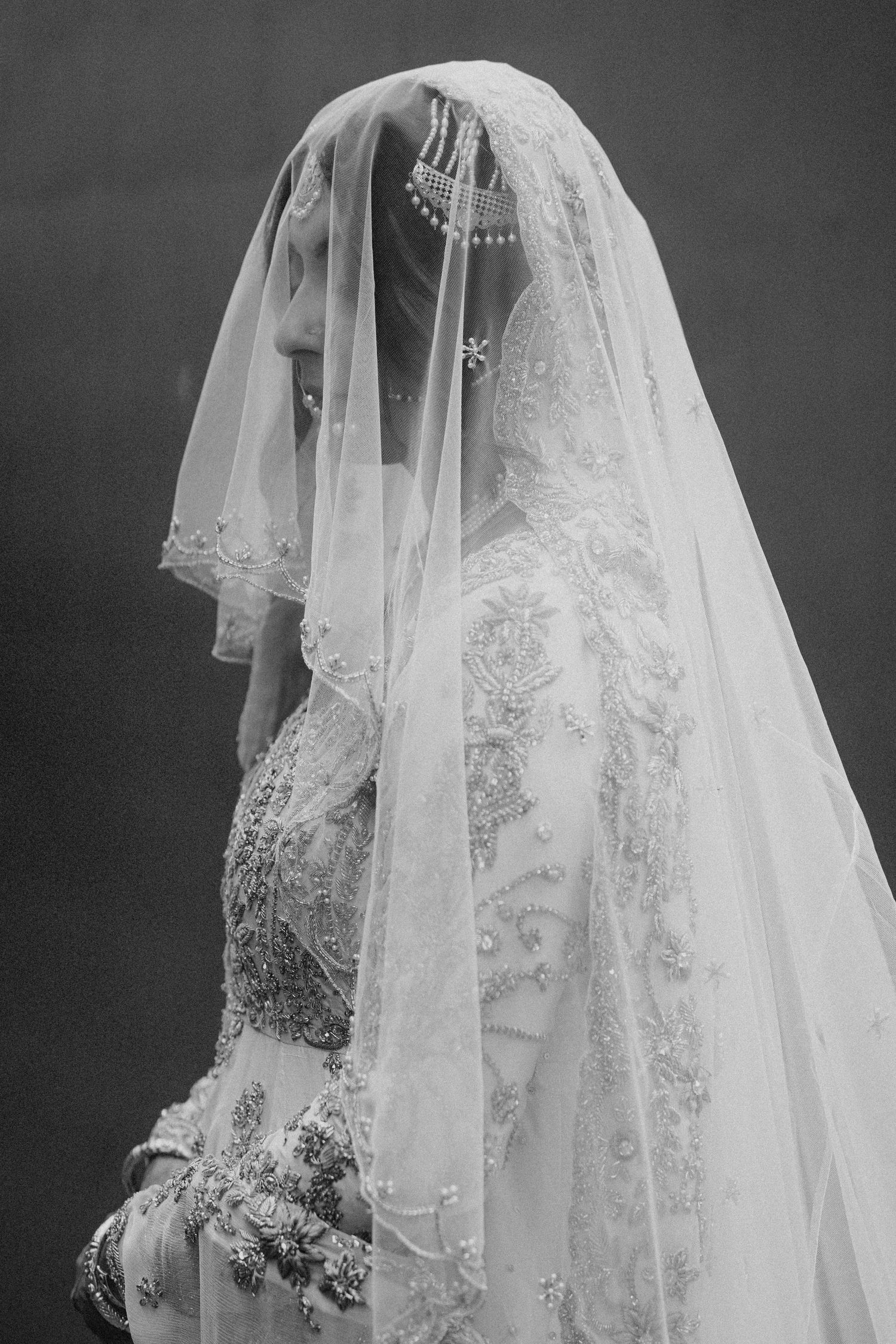 A vintage black and white photograph showing an ornate bridal veil with delicate lace details and beaded embellishments.
