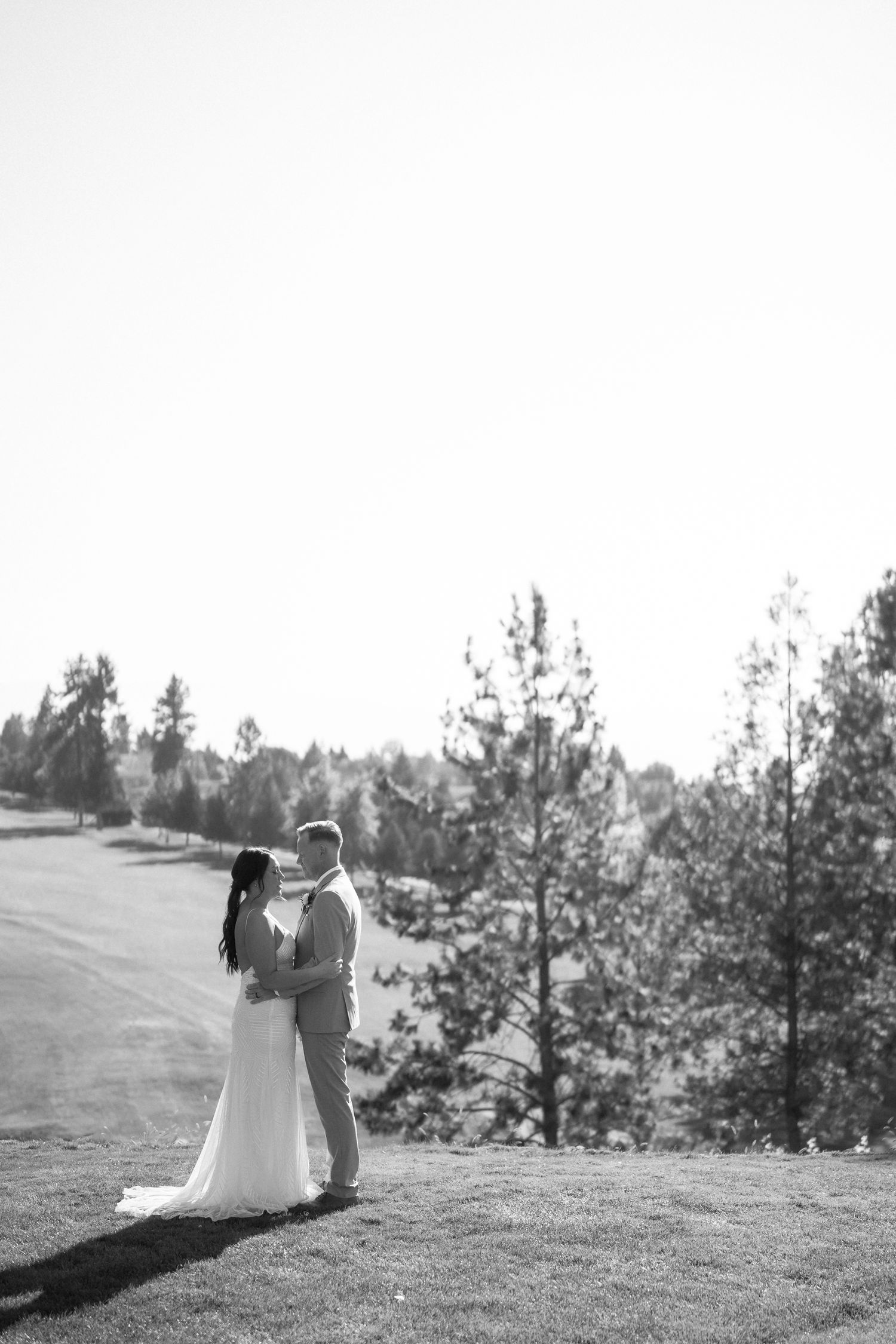 Black and white wedding portrait on a hillside with pine trees.