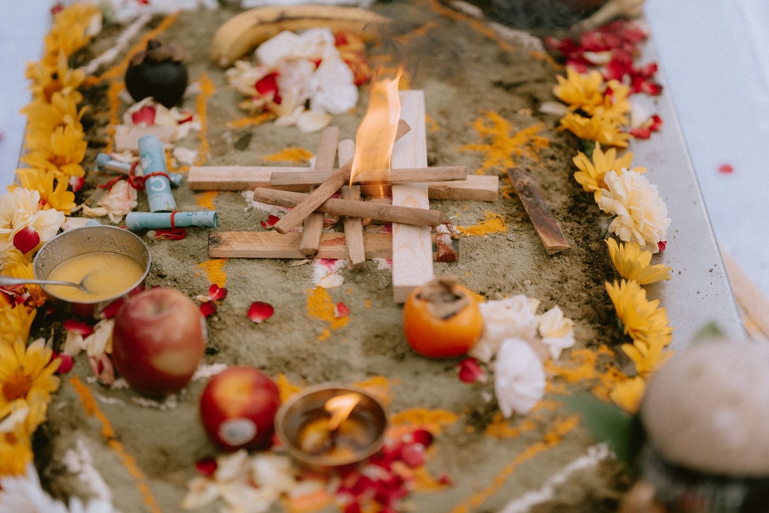A ceremonial altar with lit candles, fruits, and yellow marigold flowers for a traditional ritual.