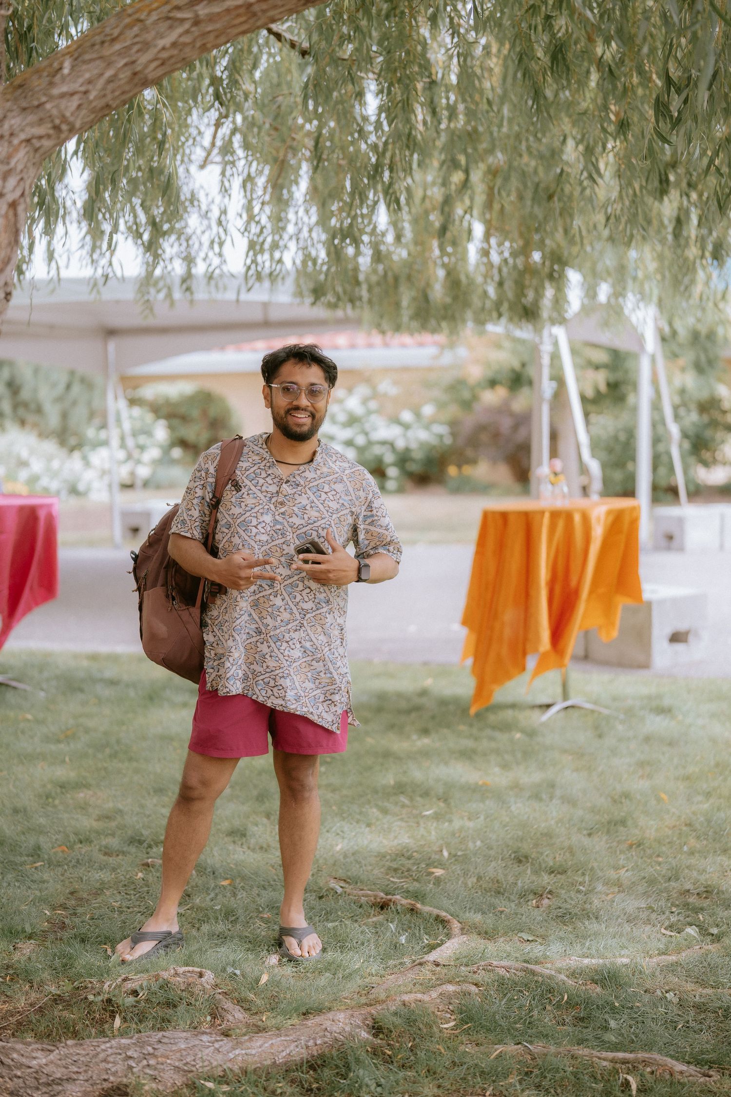 Colorful laundry hanging on clotheslines outdoors with orange and pink garments visible under willow trees.