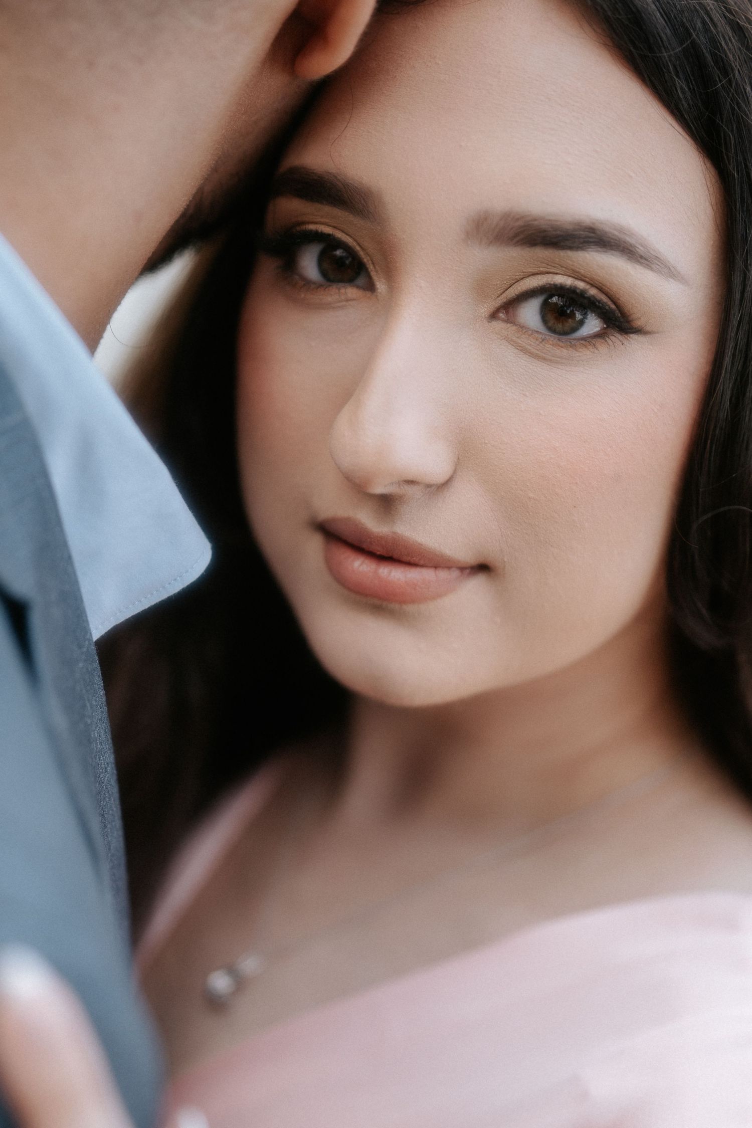 Close-up portrait of a woman with dark hair and natural makeup in soft lighting.
