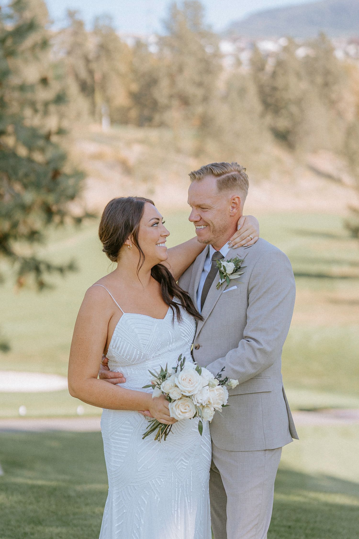 Wedding couple shares joyful laughter during their outdoor photoshoot on a golf course.