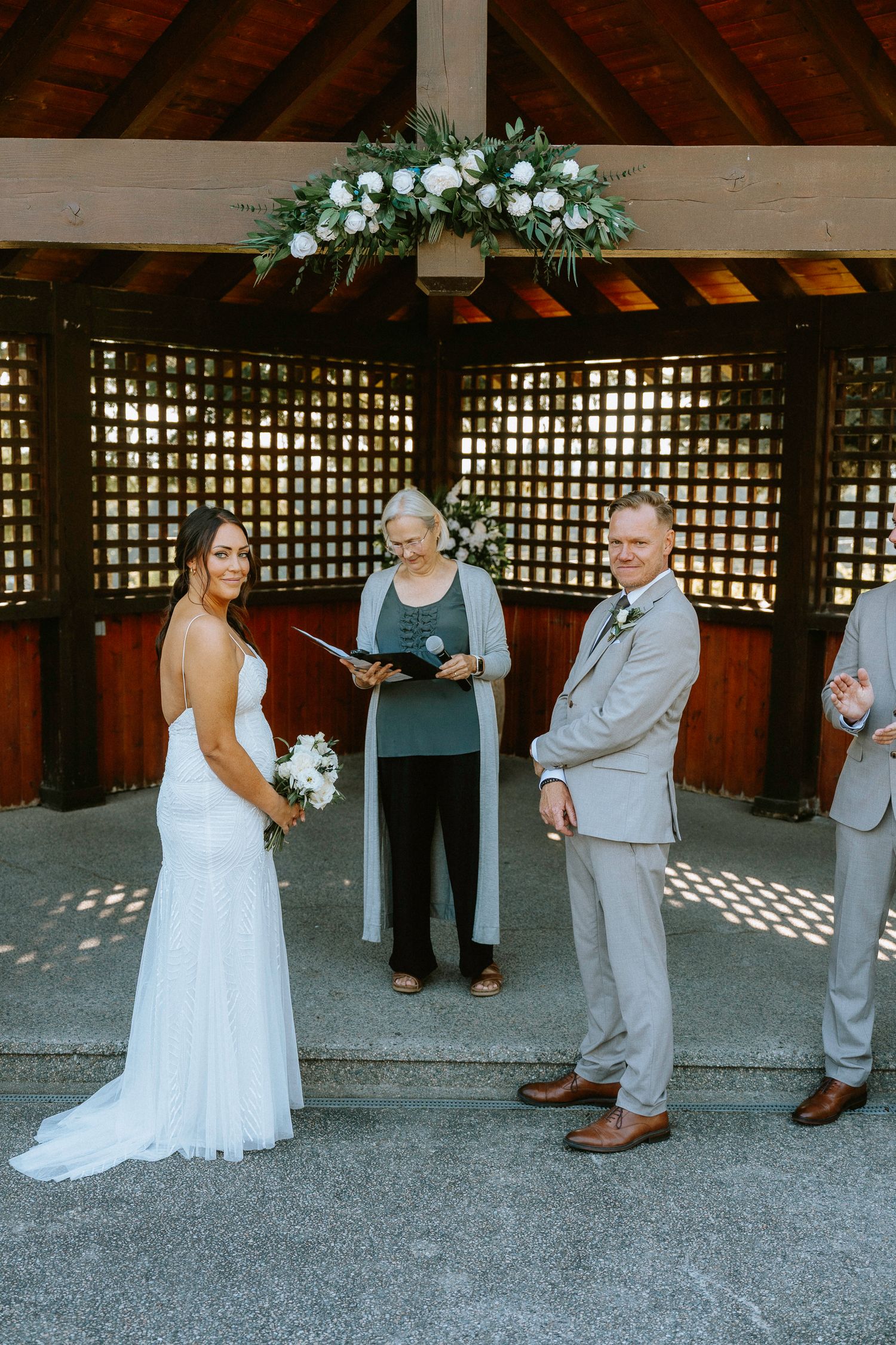 Bride and groom share their first look moment under a rustic wooden pergola.