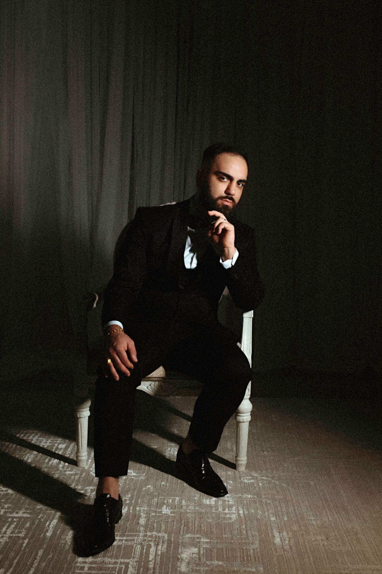 Dramatic photo series showing a person in black attire seated on a white chair against a dark background.