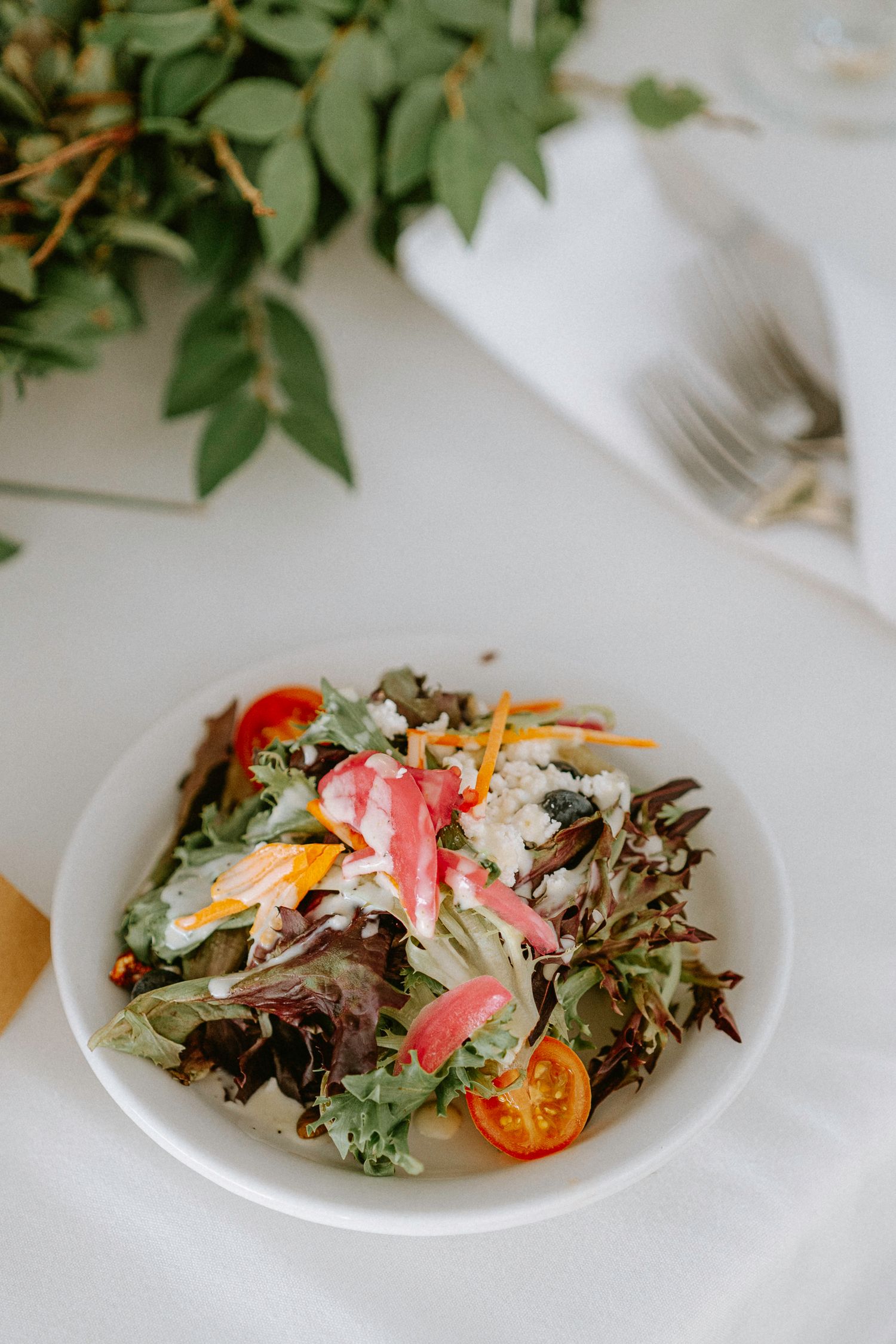 Fresh garden salads with colorful tomatoes and greens plated for wedding reception.
