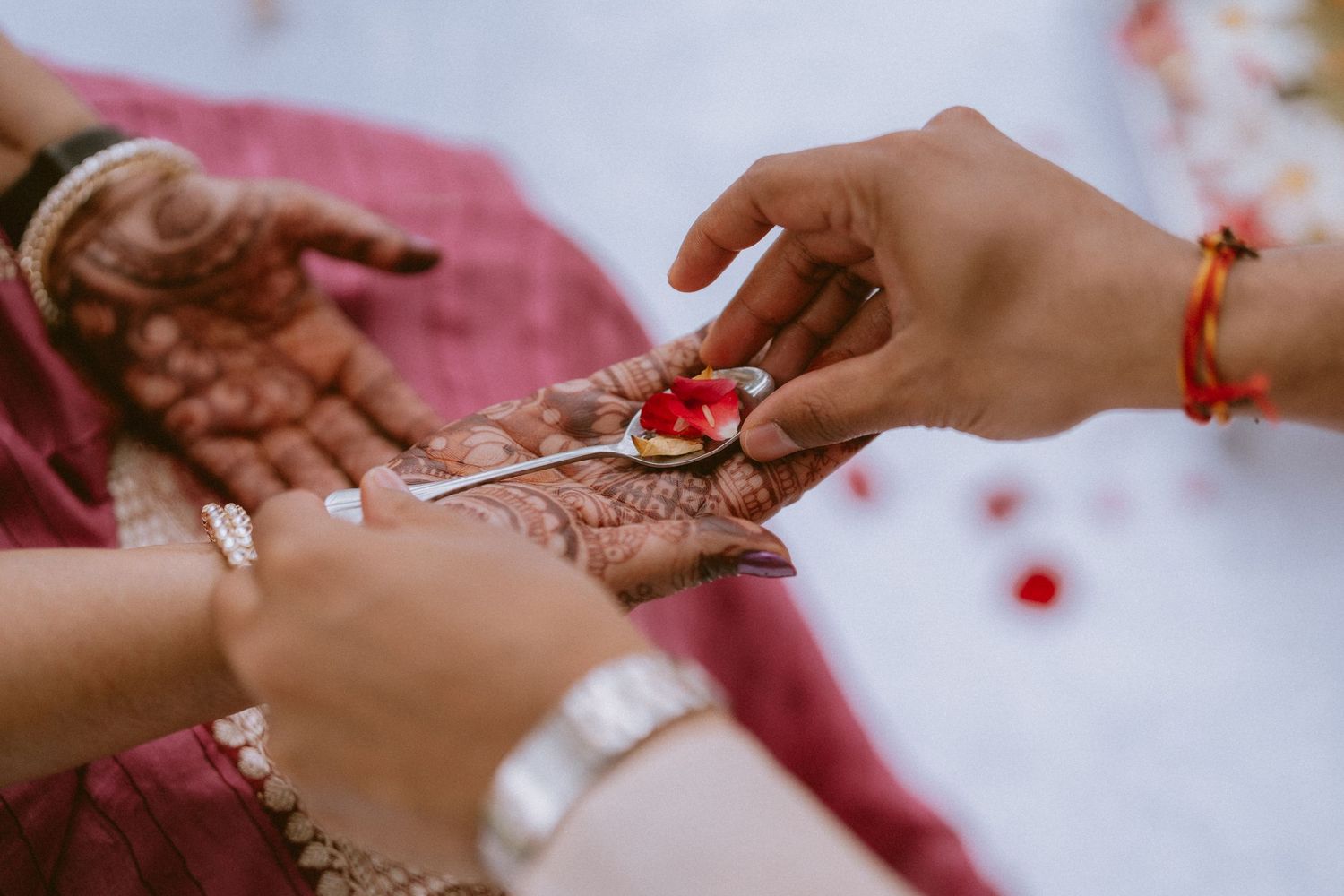 Close-up view of intricate henna designs being applied to hands during a traditional Indian wedding ceremony.
