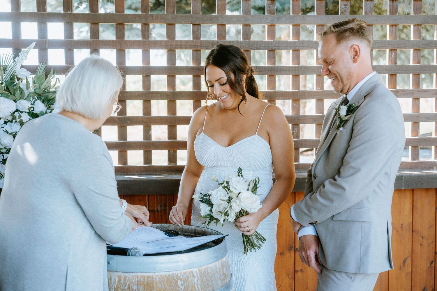 A wedding couple shares intimate moments in a rustic venue with wooden lattice walls and natural lighting.