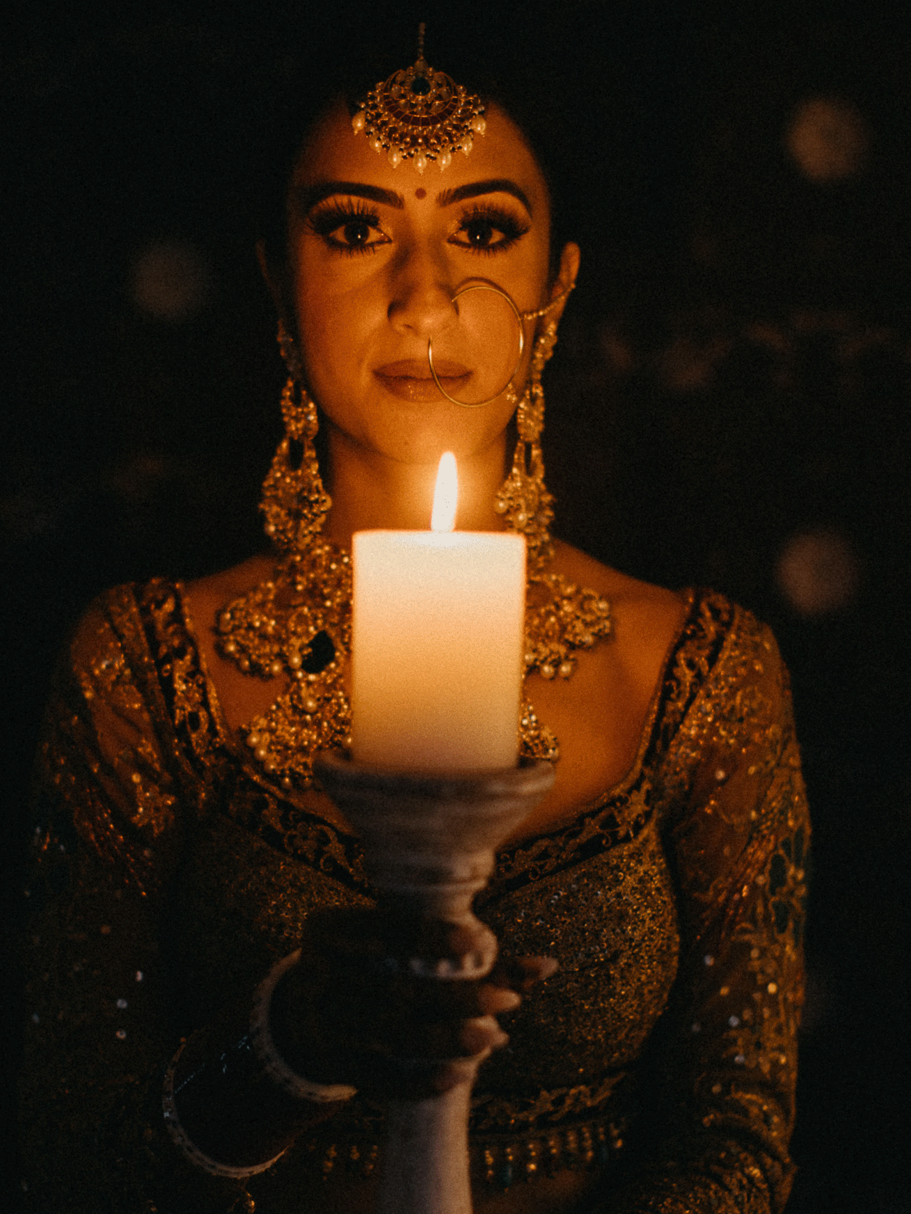 A series of moody candlelit portraits showing a person in ornate traditional Indian bridal jewelry and attire.