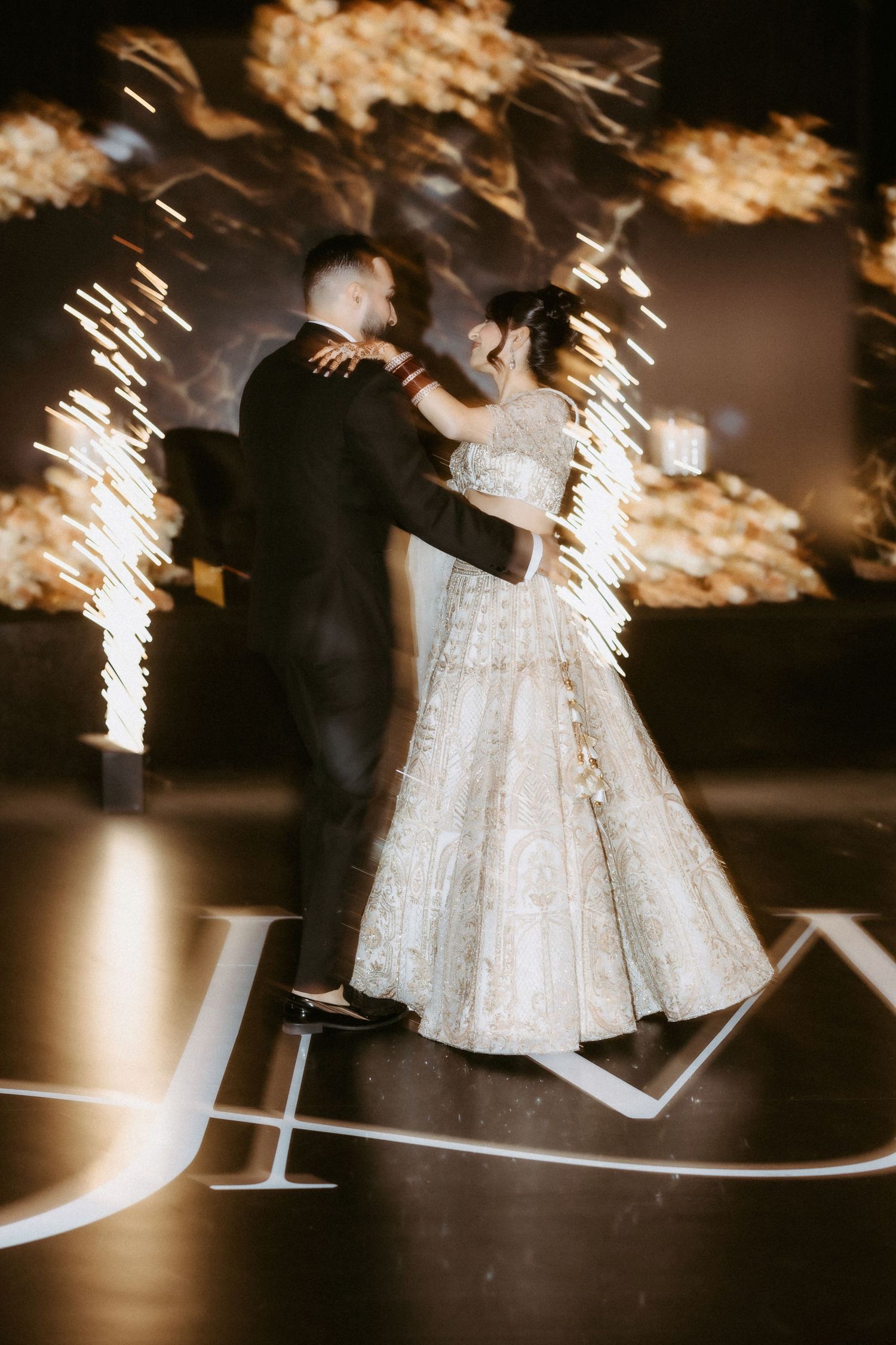 A couple dancing at their wedding reception with dramatic sparkler effects in the background.