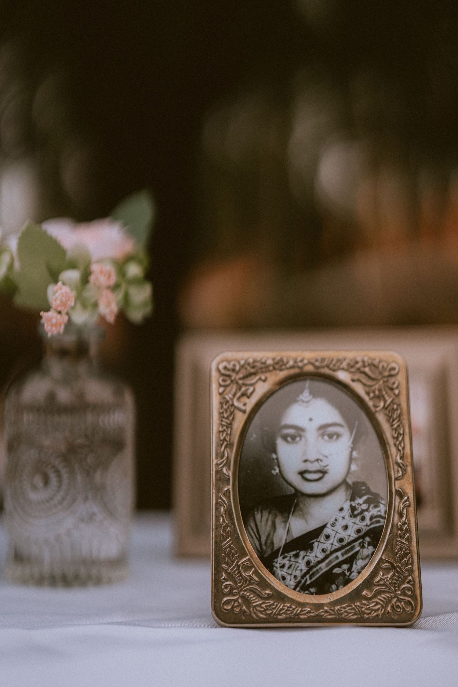 Vintage black and white portrait photographs displayed in ornate bronze frames on a table with soft bokeh background.