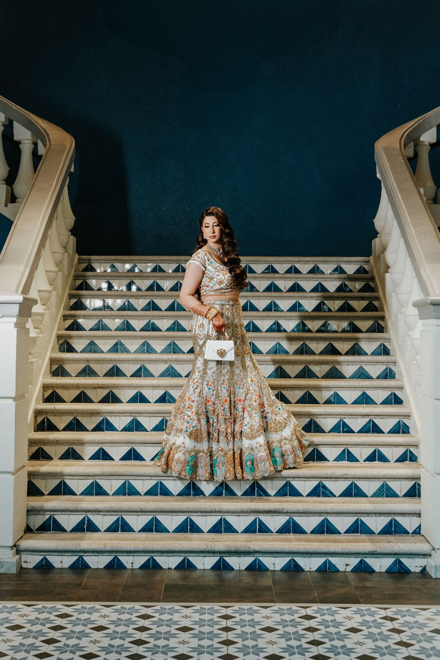 A person in a floral dress sits gracefully on geometric patterned stairs with blue and white triangular designs.