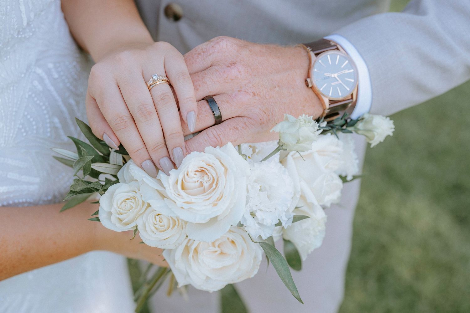 Close-up details of white rose bouquets and wedding rings.