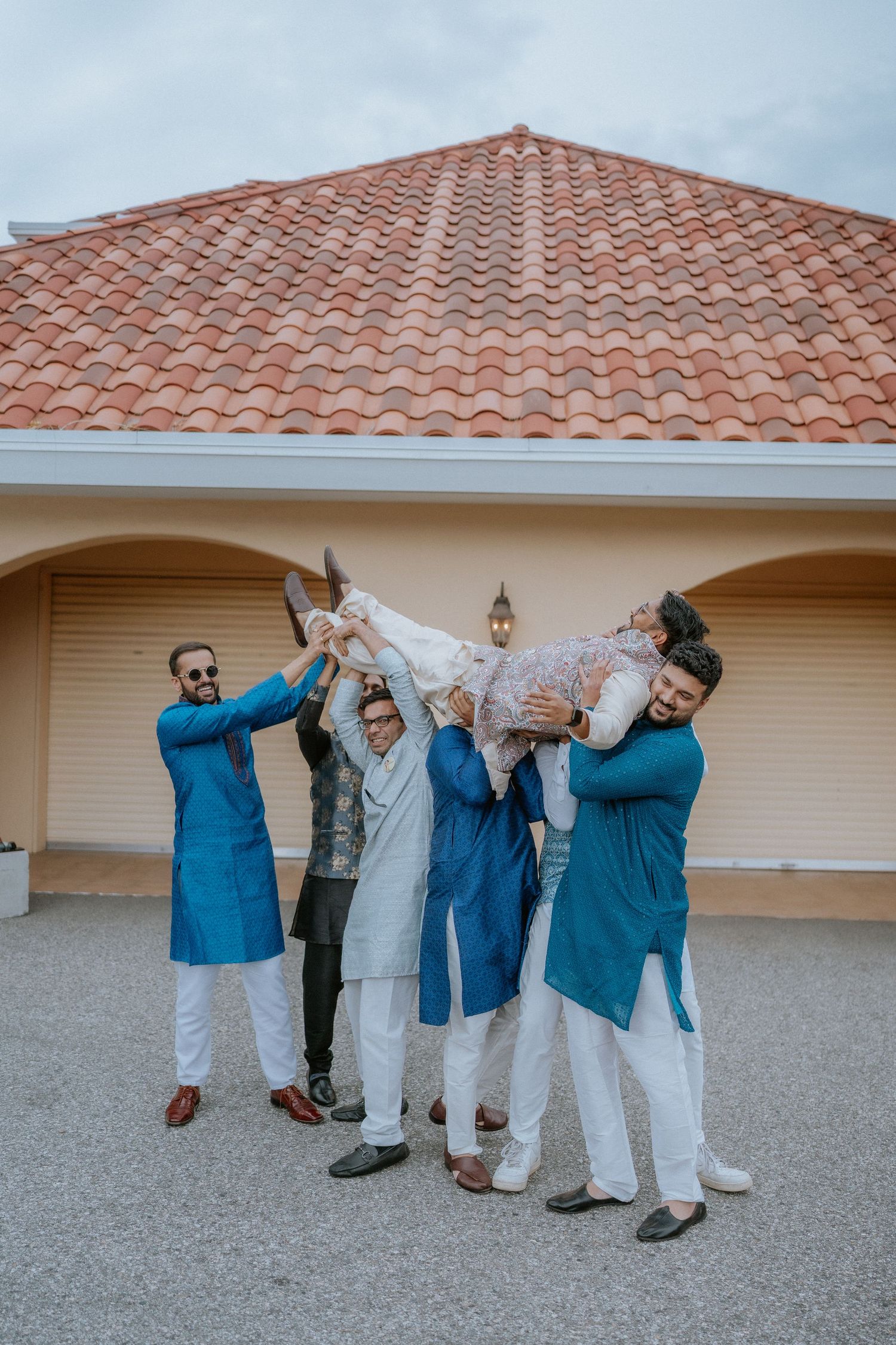 A fun sequence of wedding party members in blue and white outfits dancing and posing playfully on a concrete patio.