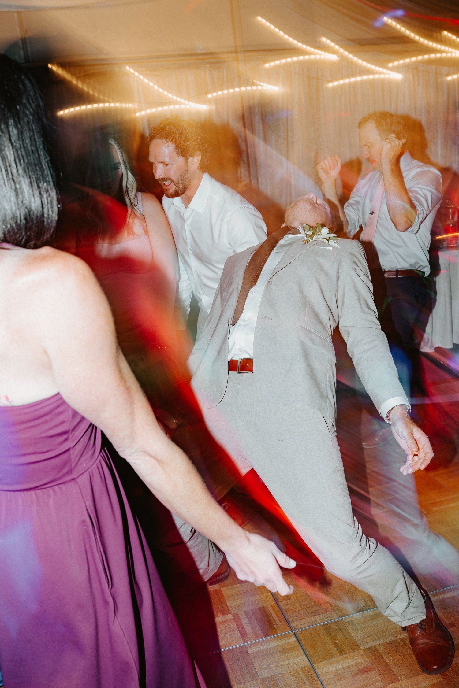 Wedding reception dance floor moments captured with motion blur and colorful lighting effects.