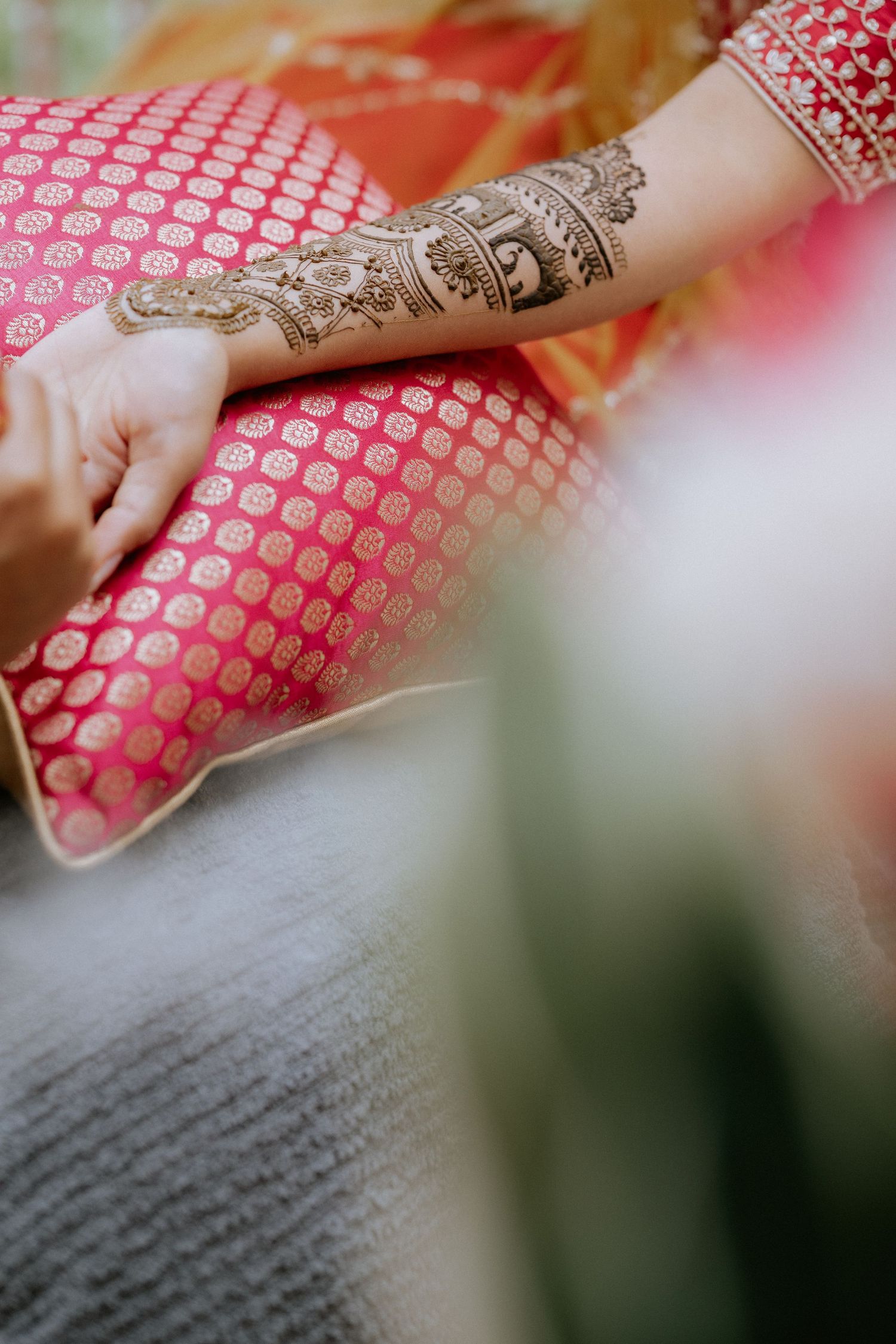 Intricate henna designs adorn hands wearing traditional Indian bridal jewelry and red bangles.