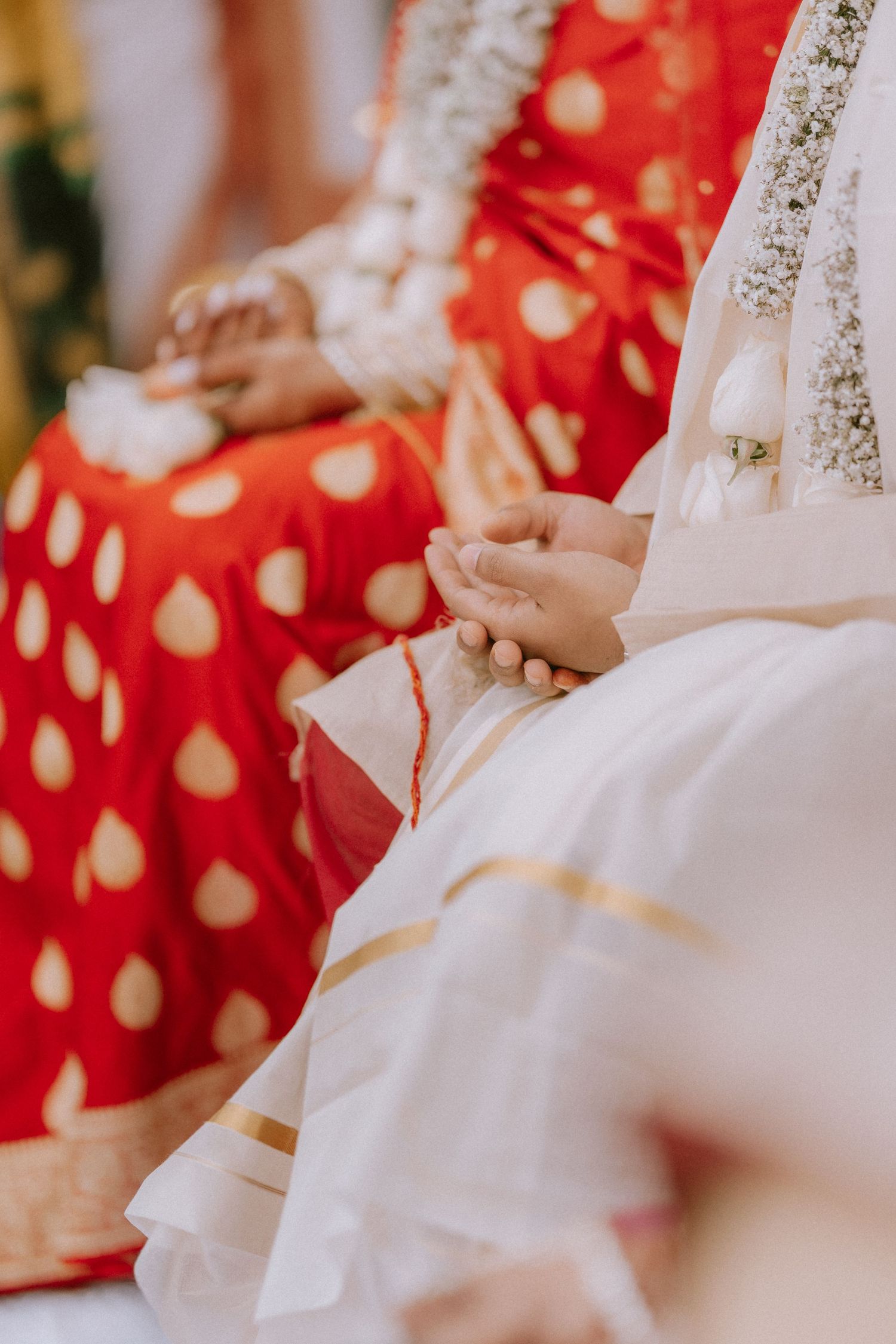 Close-up details of red and white traditional wedding attire with intricate embellishments.