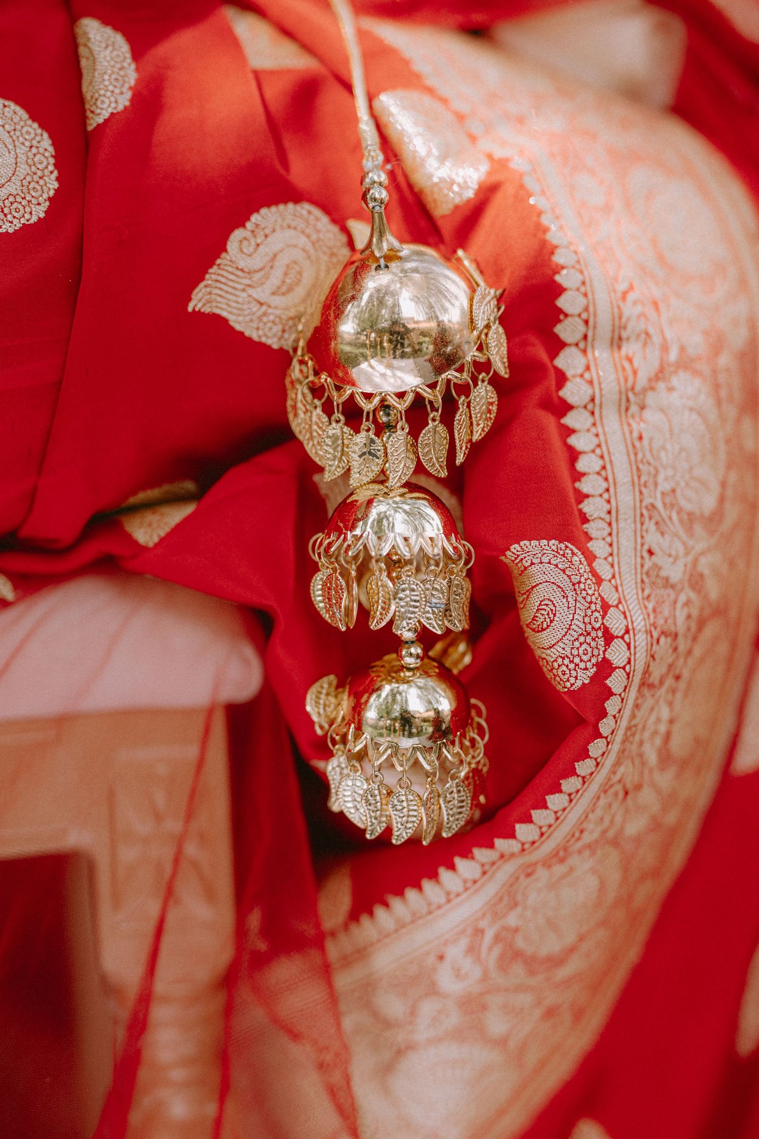 Close-up of ornate gold jewelry and accessories against red traditional wedding attire.