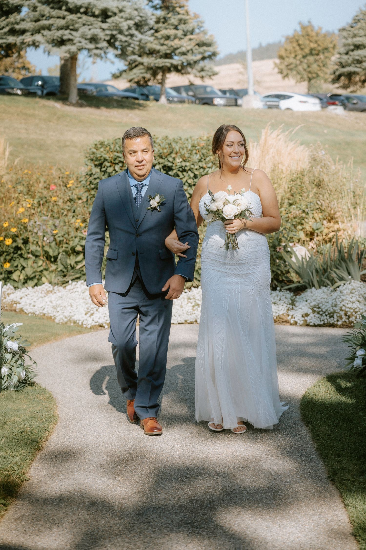 Wedding party members walking along an outdoor garden path.
