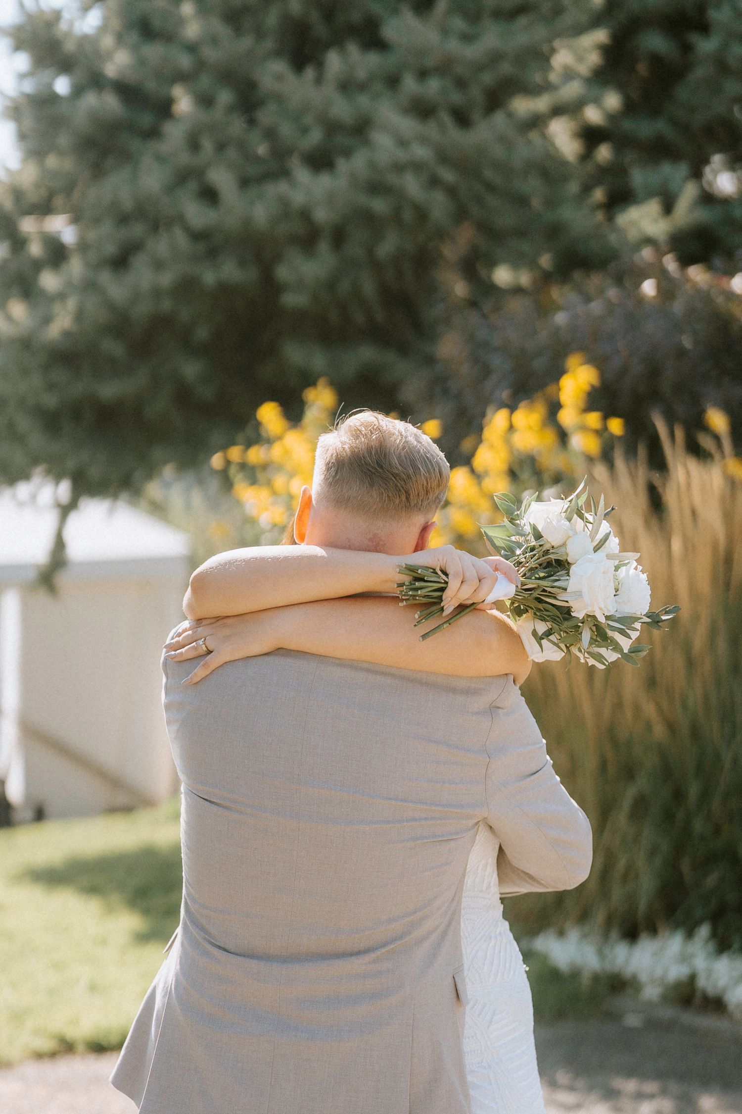 Intimate wedding moment captured during golden hour with yellow wildflowers in the background.