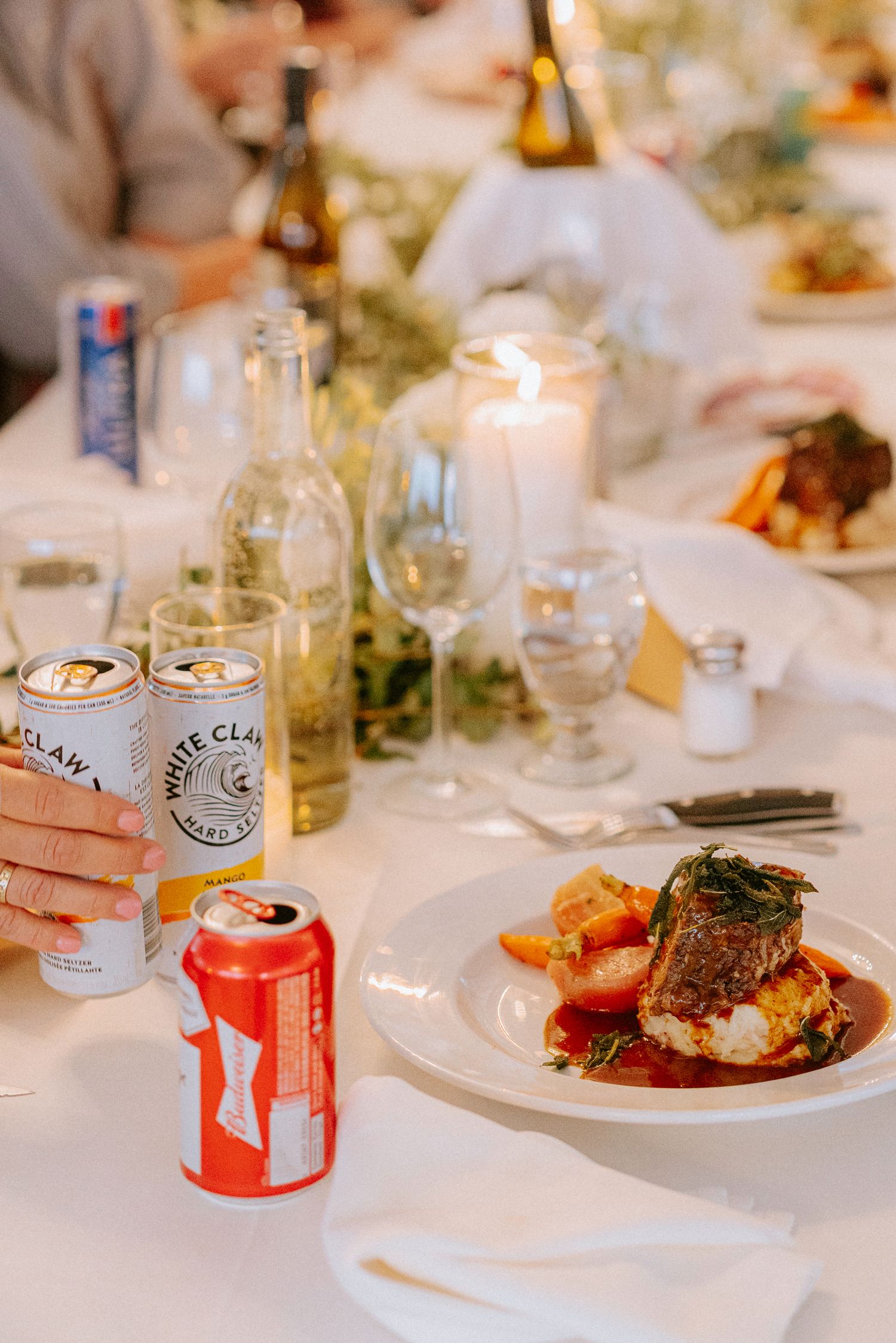 Wedding reception table with plated meals and White Claw beverages.