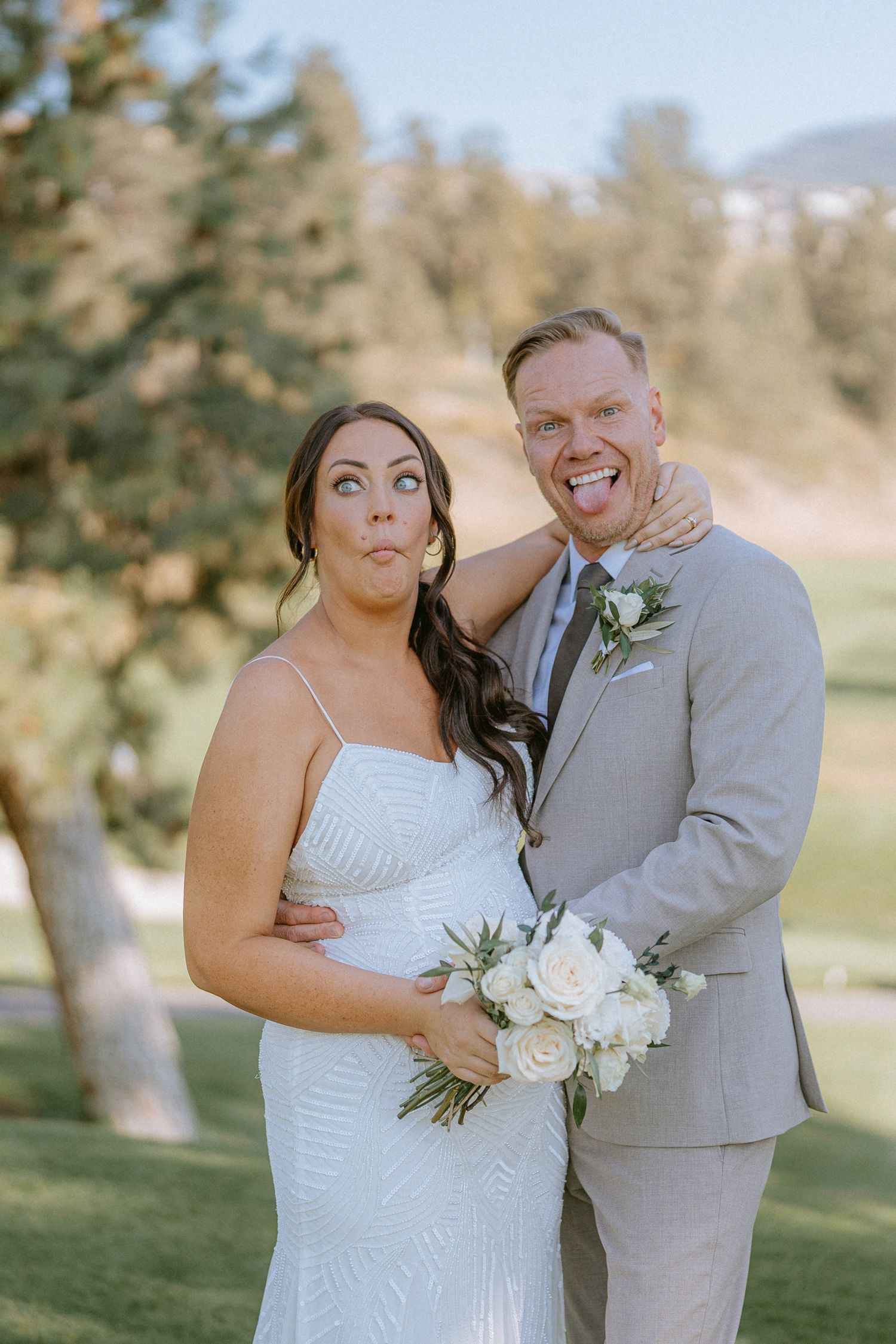 Bride in white dress and groom in light gray suit share intimate moments during outdoor wedding photoshoot.