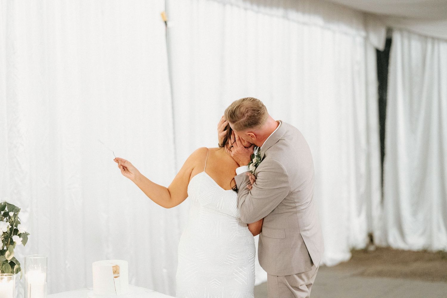 Wedding celebration inside white tent venue with dancing and festivities.