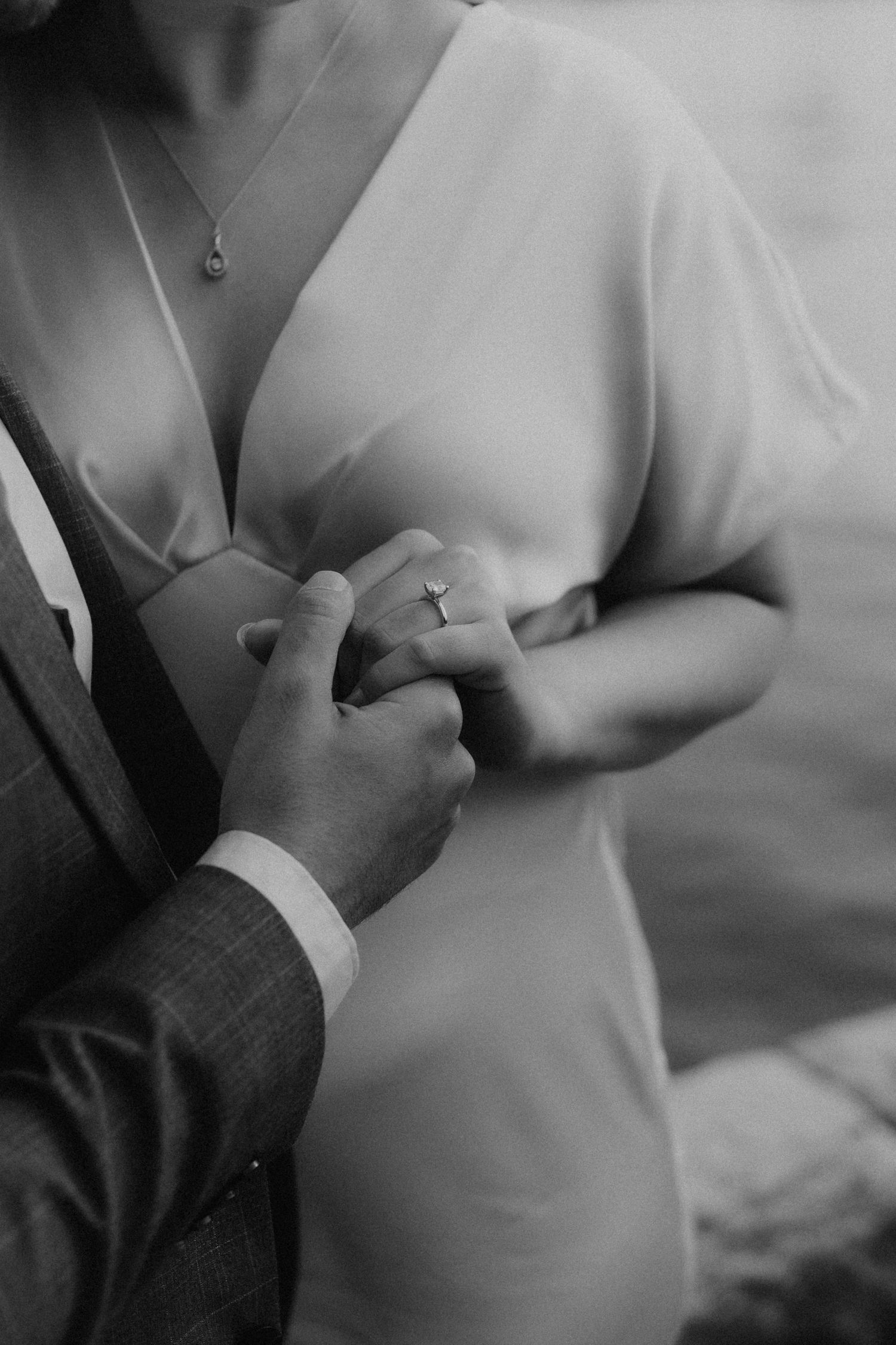 Hands adjusting a formal shirt button in black and white photography.