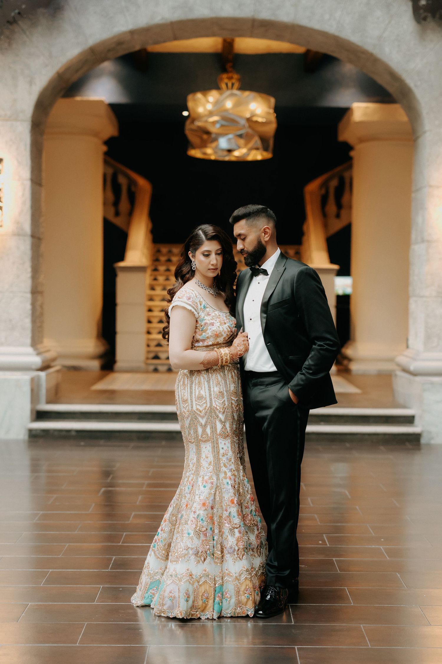 Romantic couple shares intimate moments in an elegant arched colonnade setting.