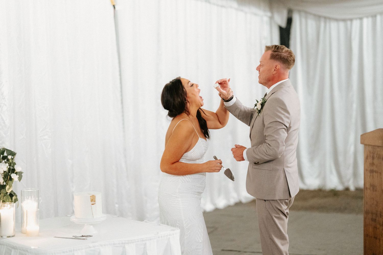 Wedding couple shares their first dance in an elegant white-draped reception venue.