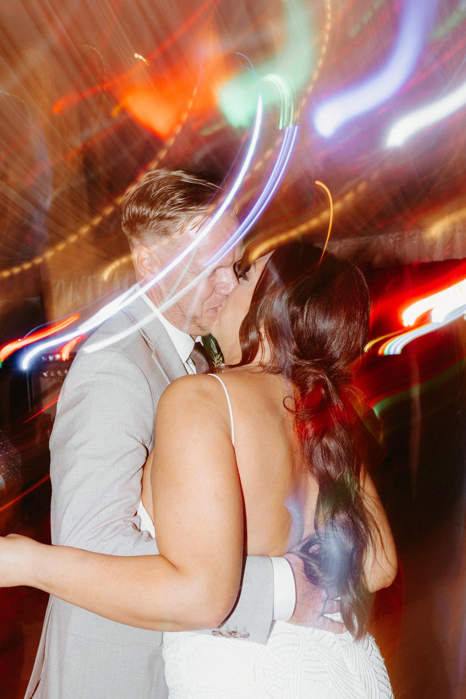 Couples dancing at wedding reception with dramatic lighting effects and motion blur.