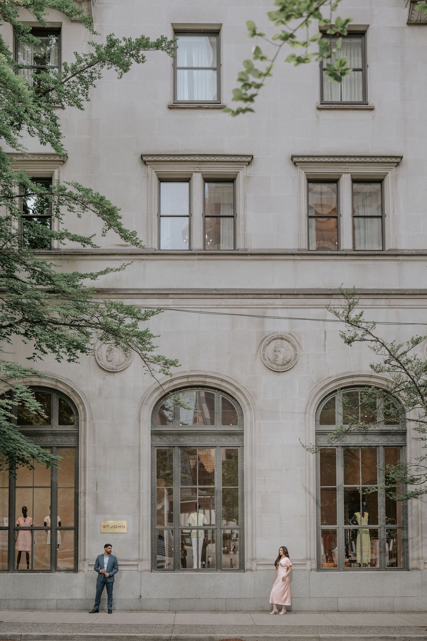 Elegant stone building facade with arched windows and people walking outside on a city street.