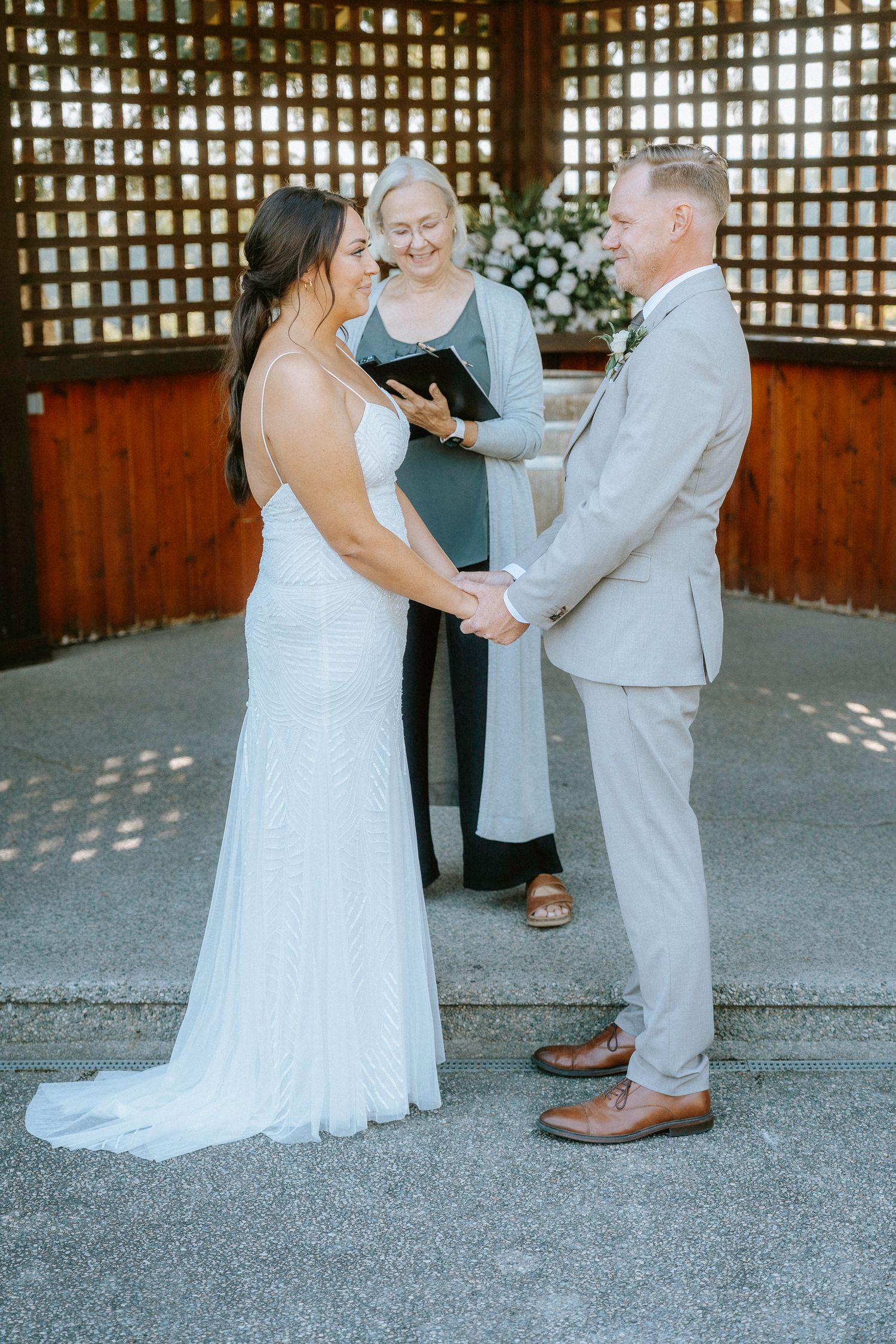 Wedding ceremony taking place under a wooden lattice structure.