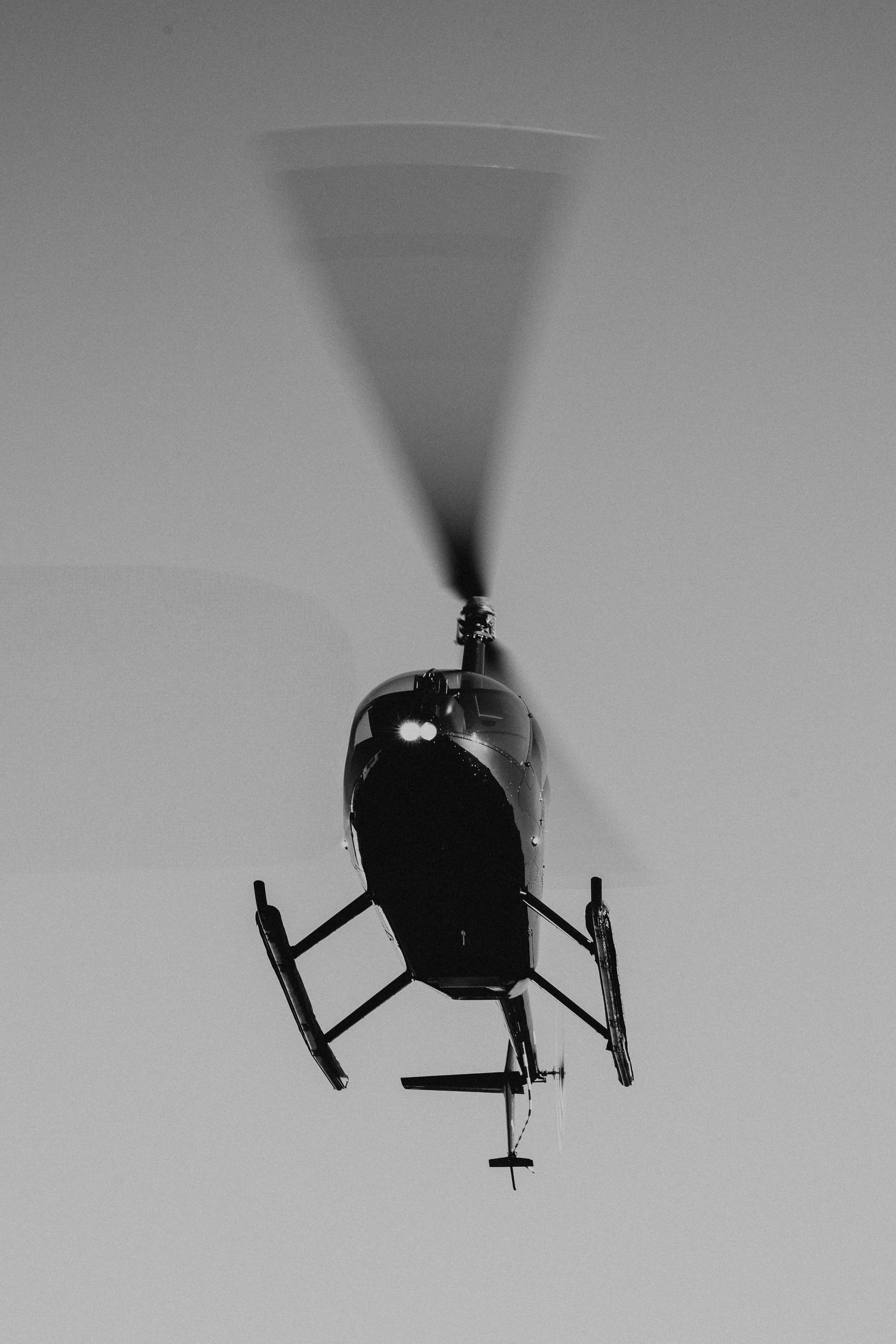 Silhouettes of helicopters in flight against a light background.
