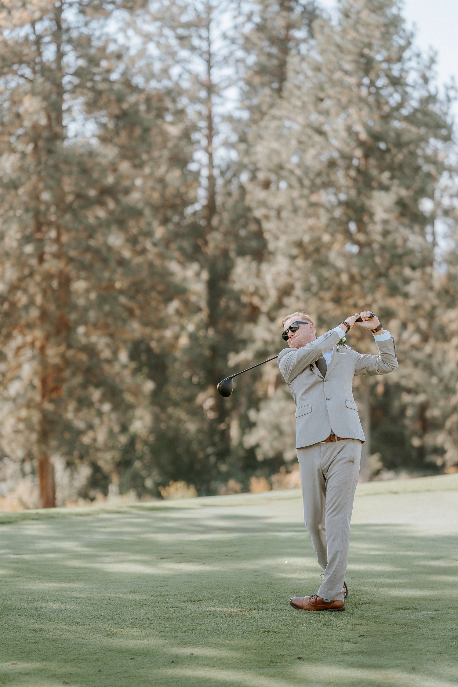 Wedding party members perform fun dance moves on a golf course green.