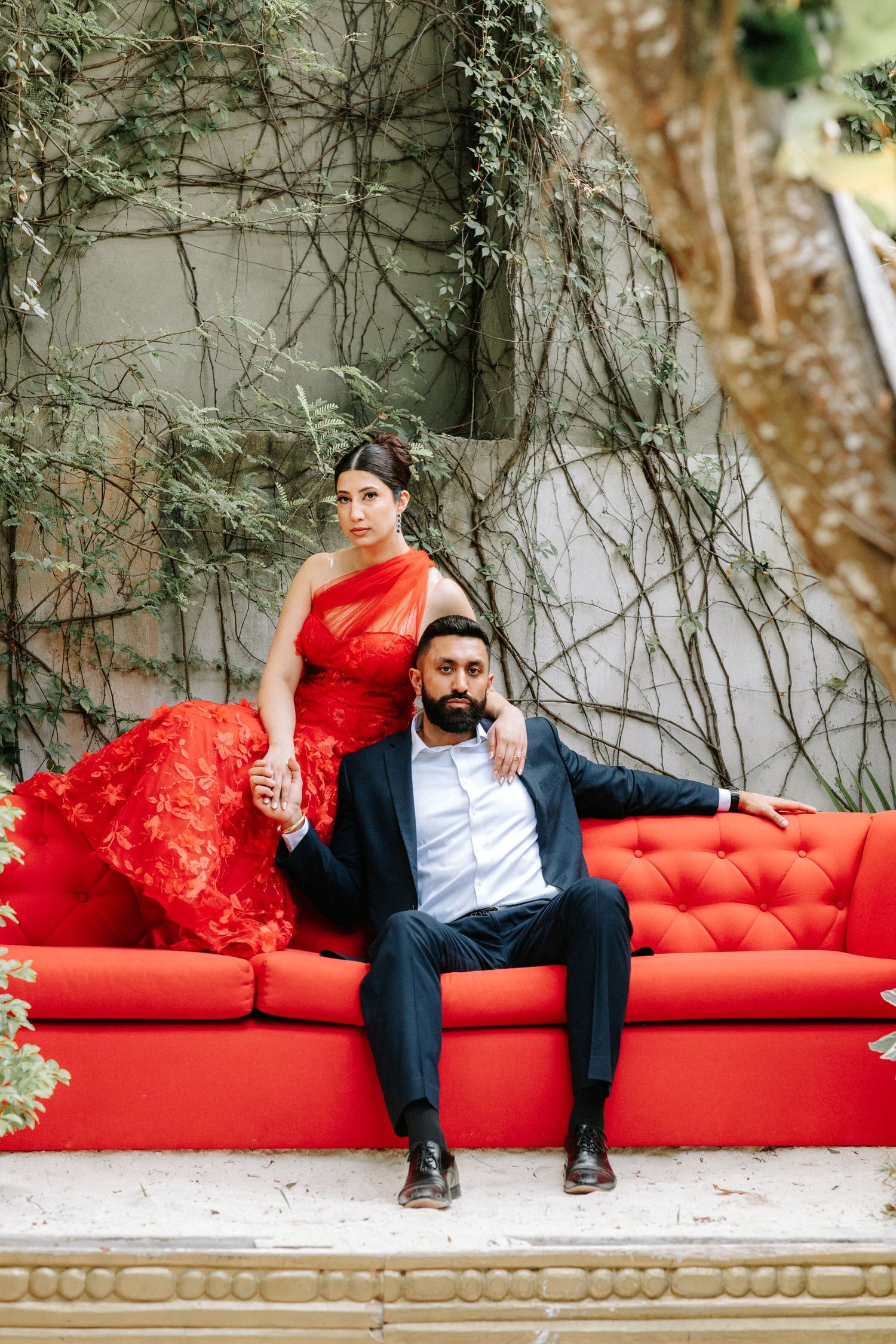 A sequence of photos showing a person lounging on a luxurious red tufted couch against a white wall with climbing vines.