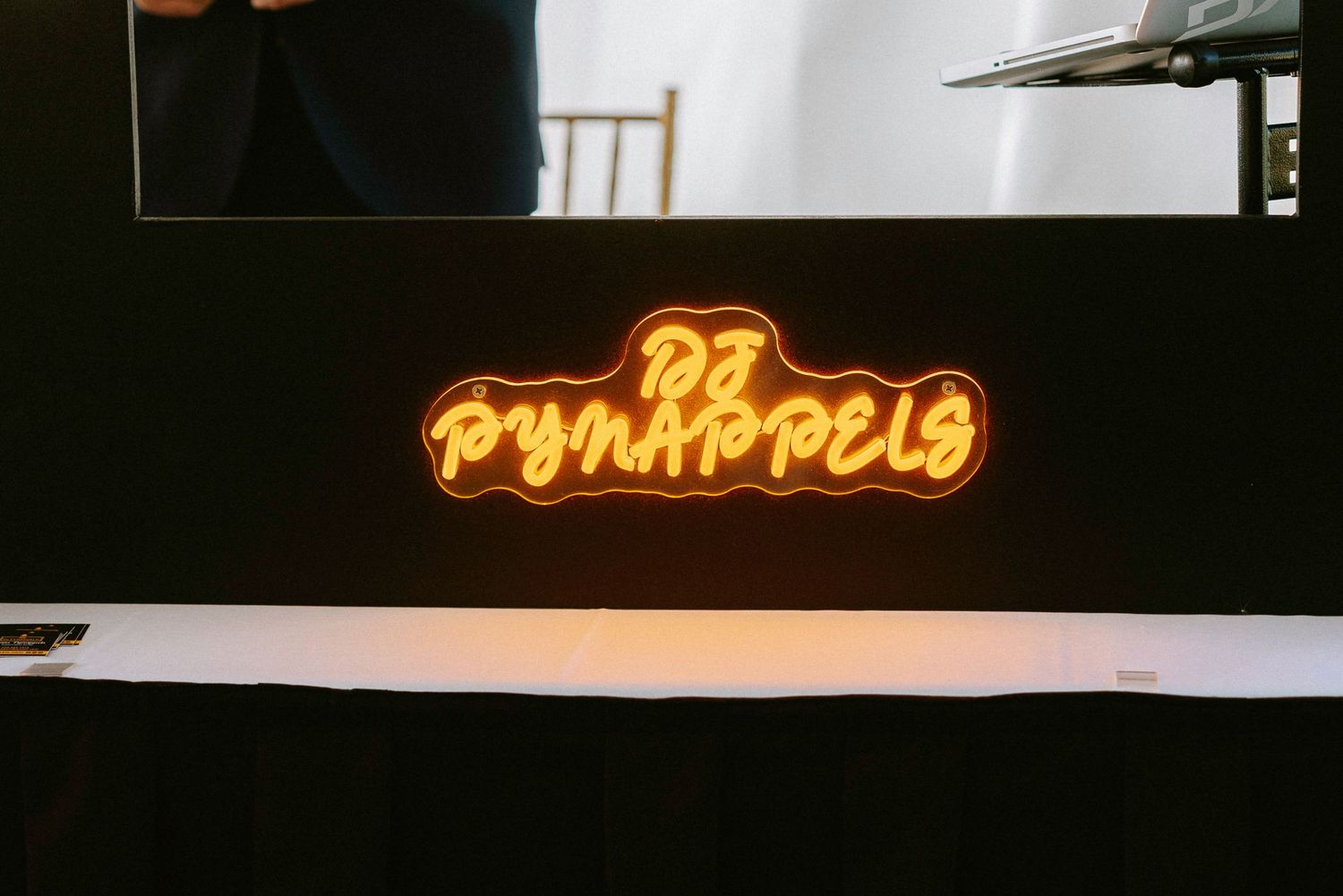 Illuminated neon signs glowing in warm orange against a dark background at a venue.